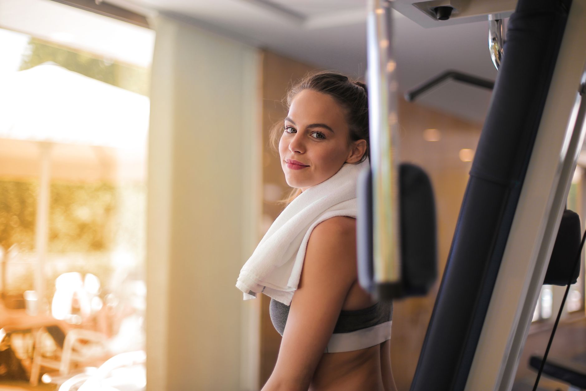 Young woman exercising in a gym with a towel around her neck, exuding health and fitness.