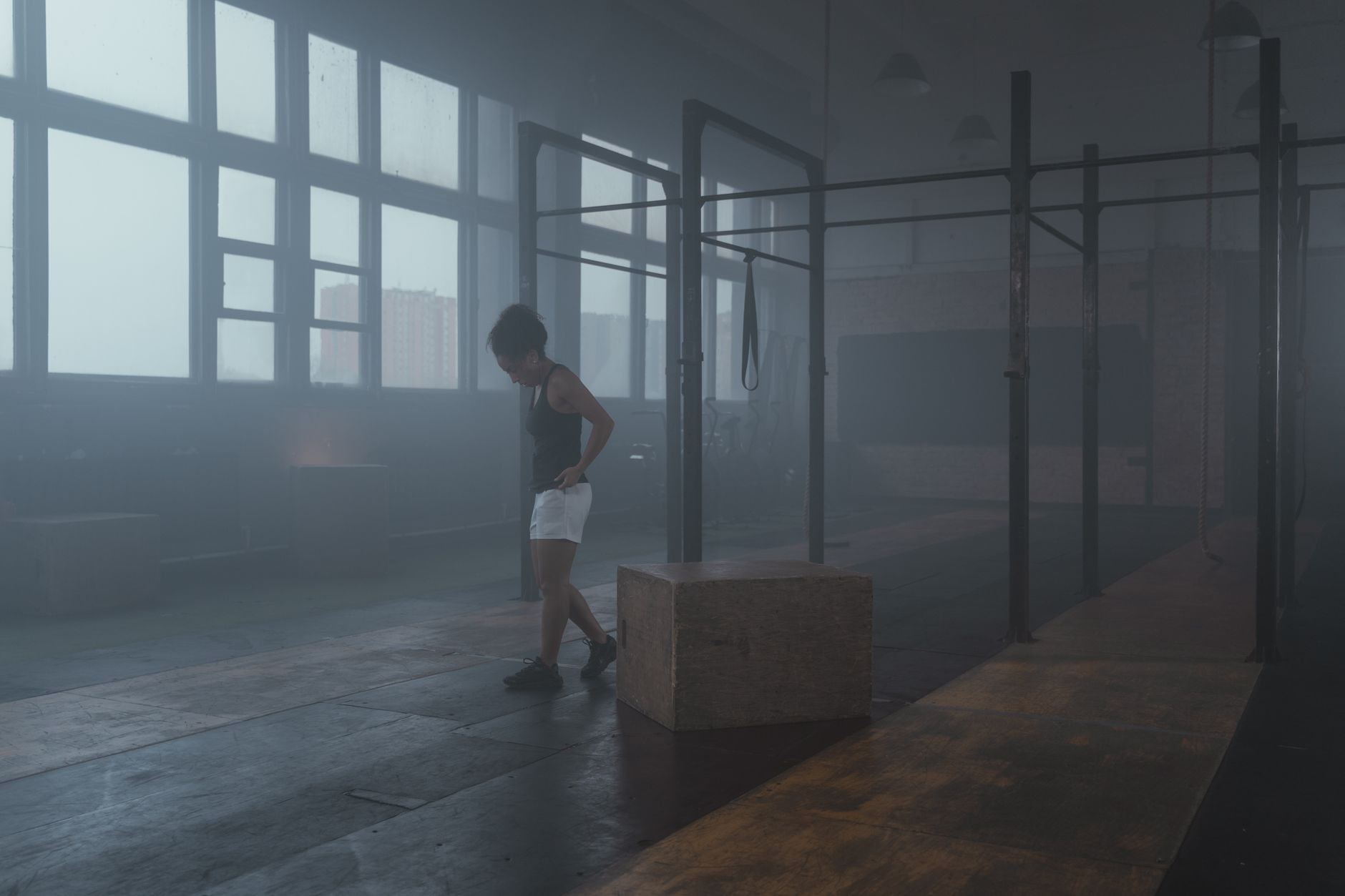 Woman exercising in a foggy gym, highlighting fitness and endurance.