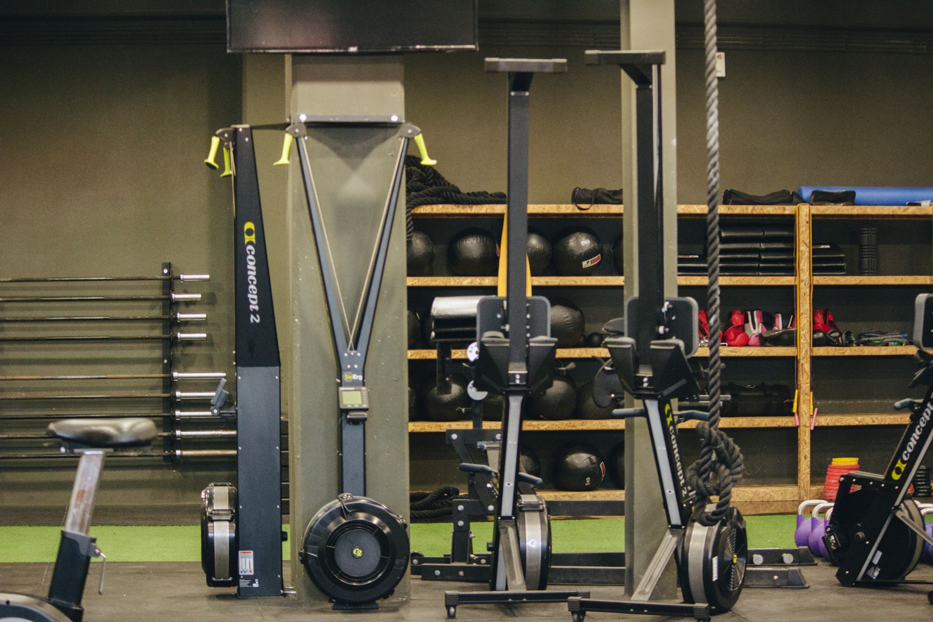 Modern gym with exercise equipment including rowing and ski machines, weights, and ropes.
