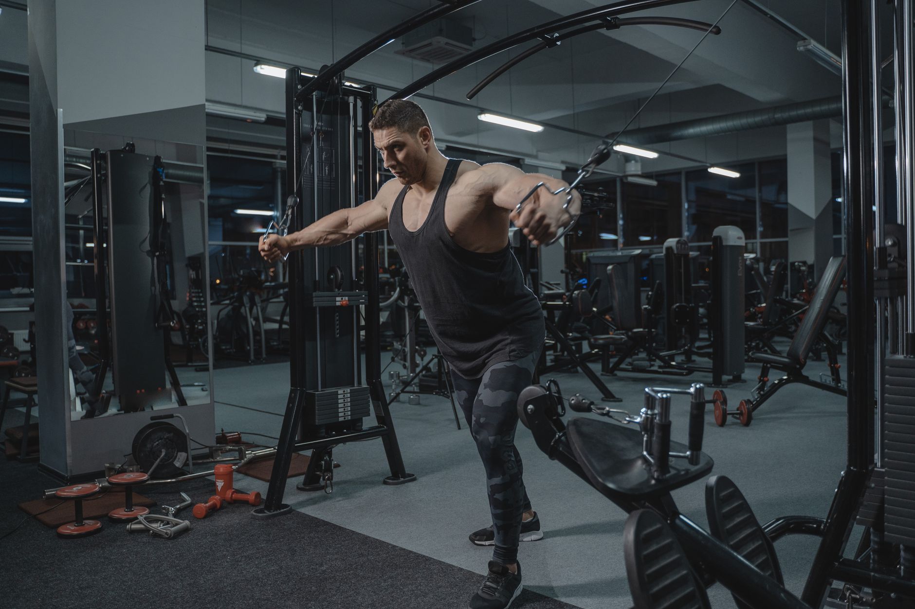 Muscular man working out in the gym using a cable crossover machine.