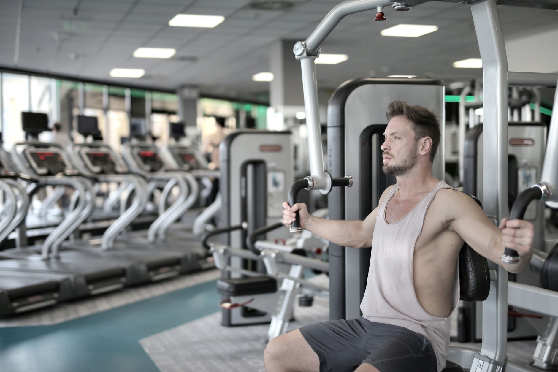 Man exercising on chest press machine in a modern gym, showcasing fitness and strength.