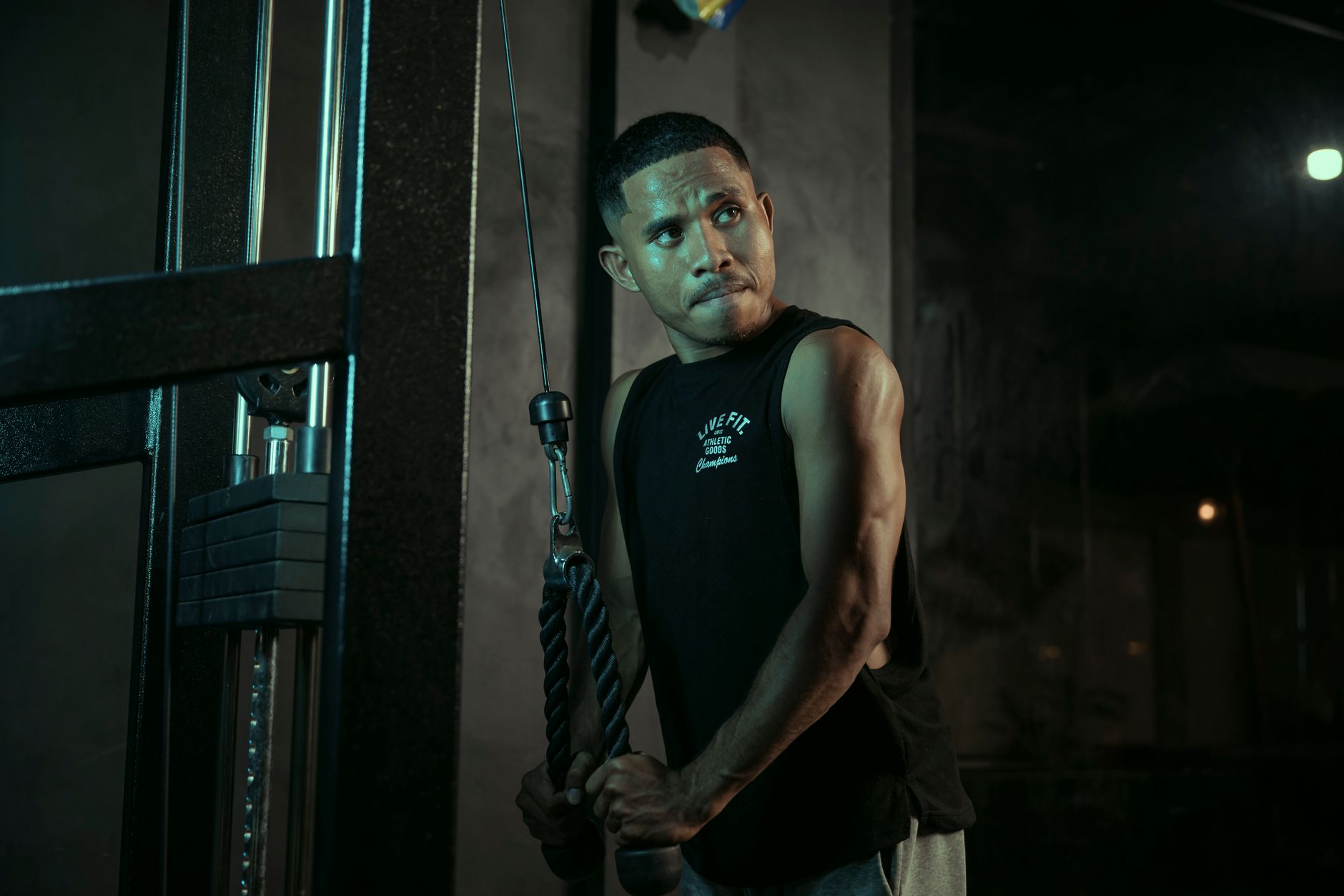 A dedicated man exercises with a cable machine in a gym, showcasing determination and strength.