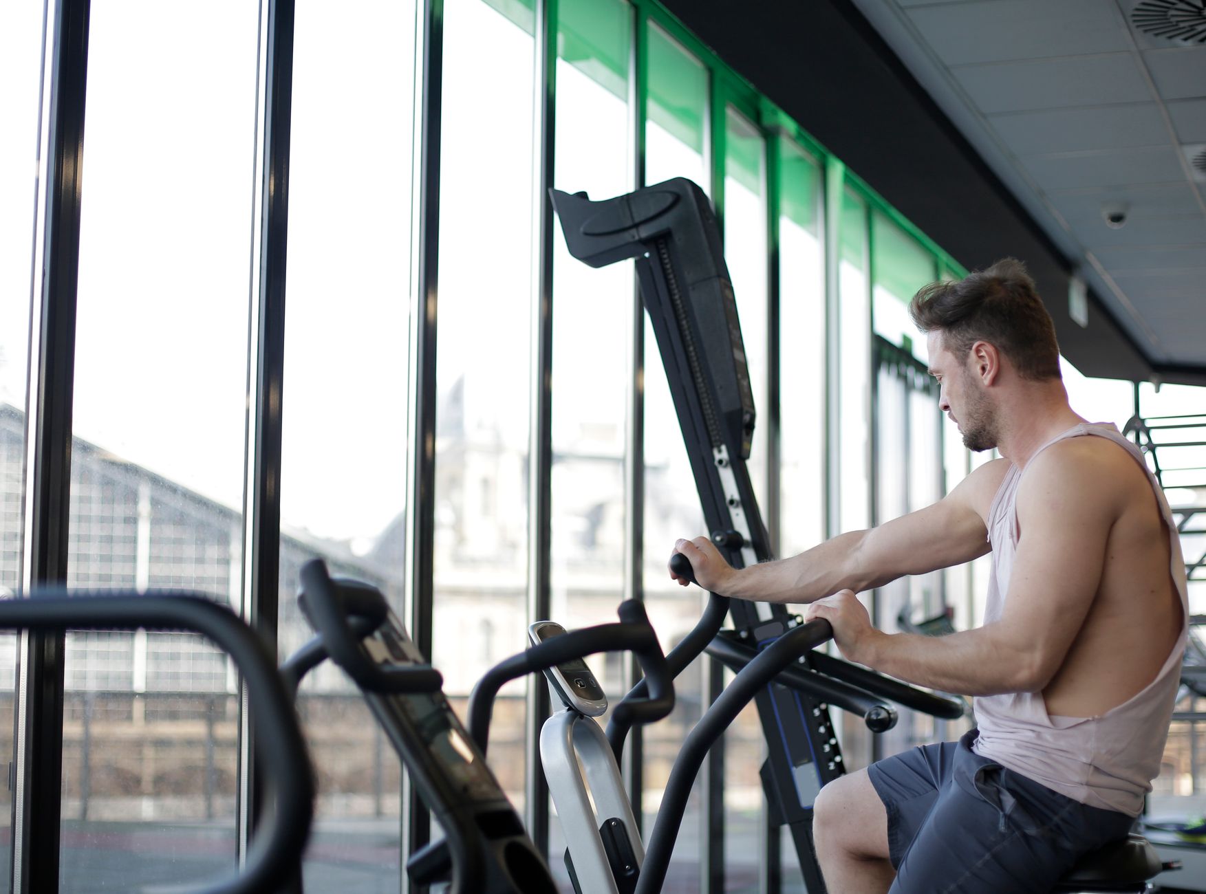 Adult man working out on a stationary bike in a modern gym, focusing on fitness and strength.