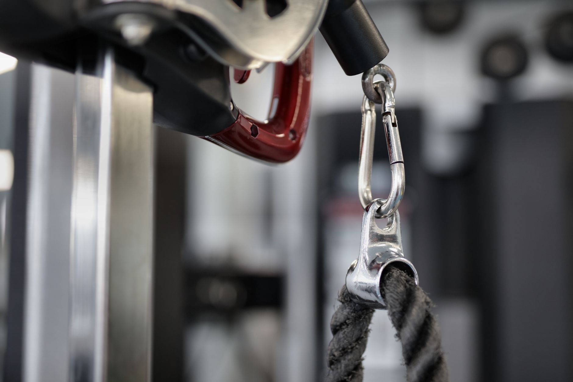 Closeup of pull down rope hanging on modern exercise machine connected with metal carabiner