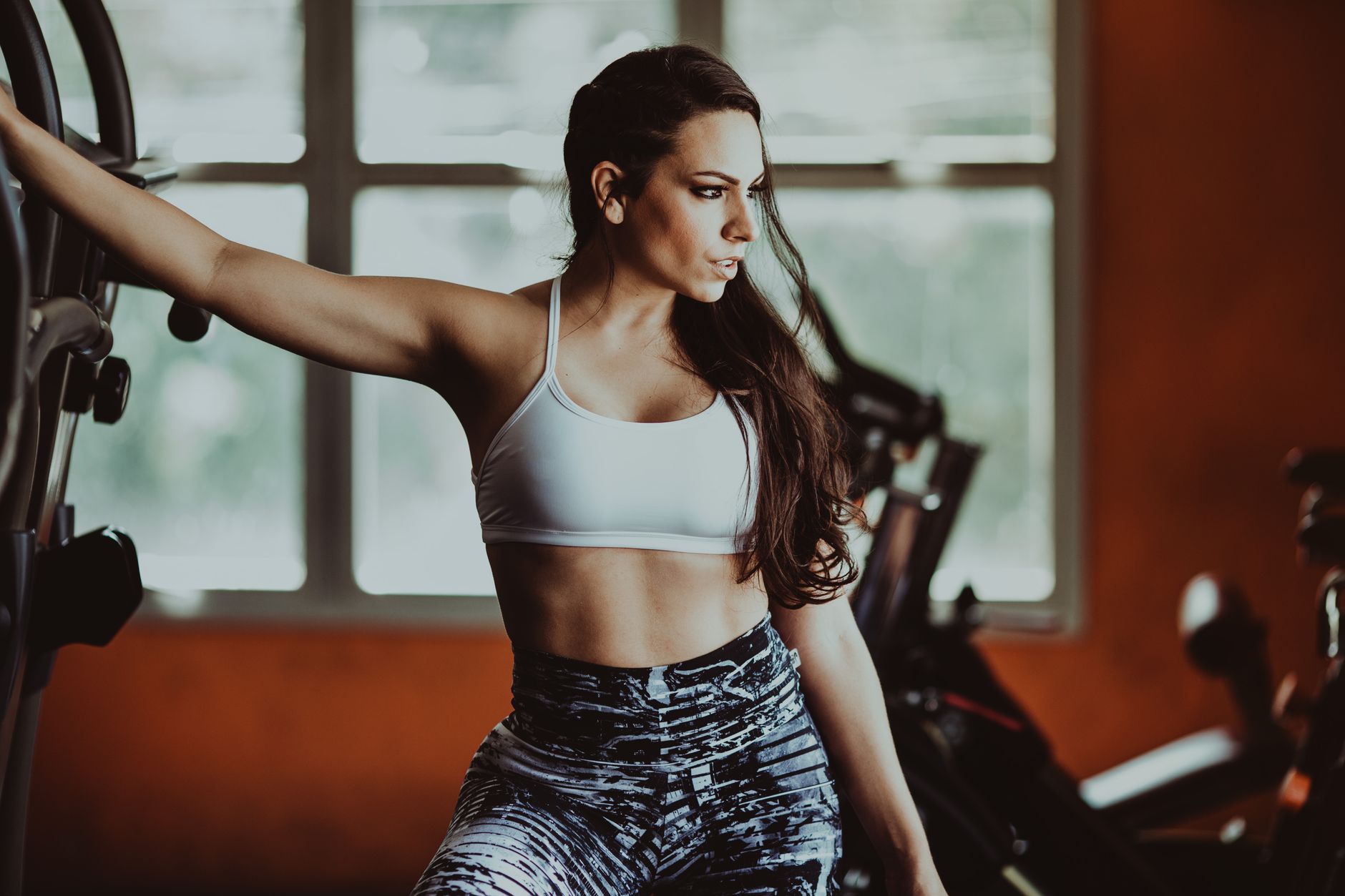 Athletic woman in sports bra posing confidently inside gym setting.