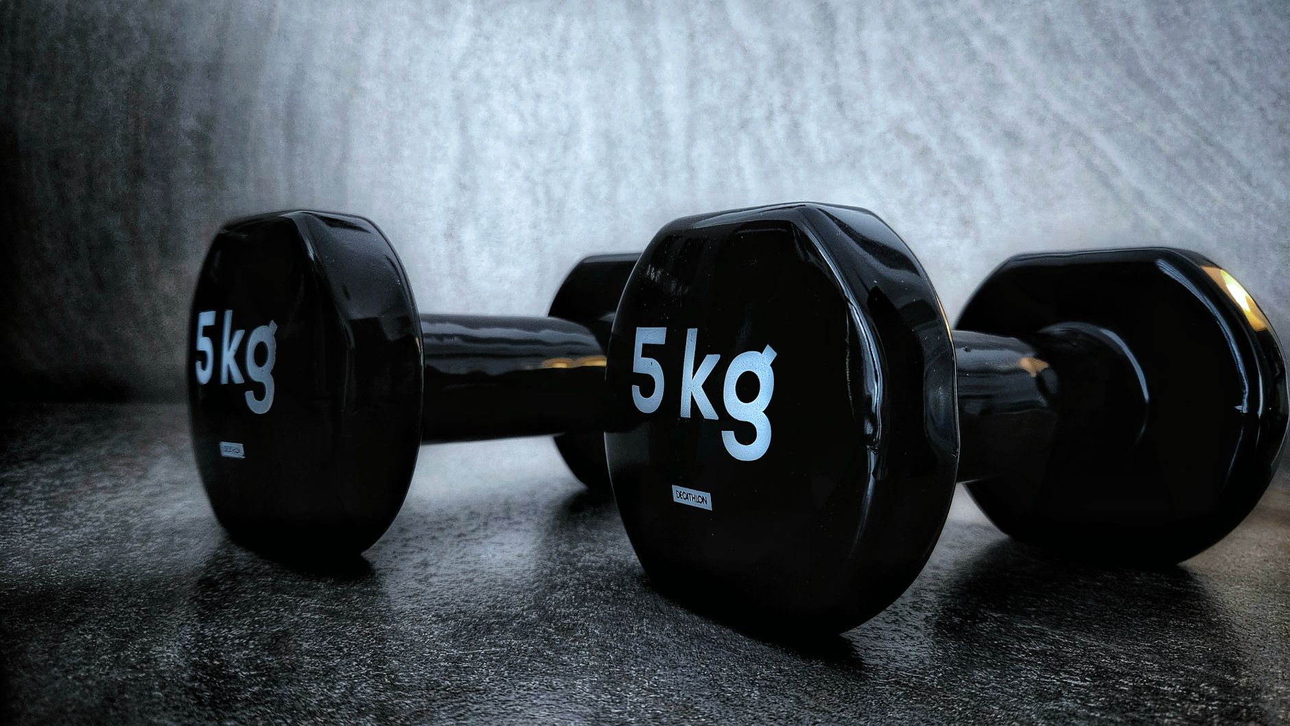 Black 5kg dumbbells on a dark background, perfect for fitness and weight training concepts.