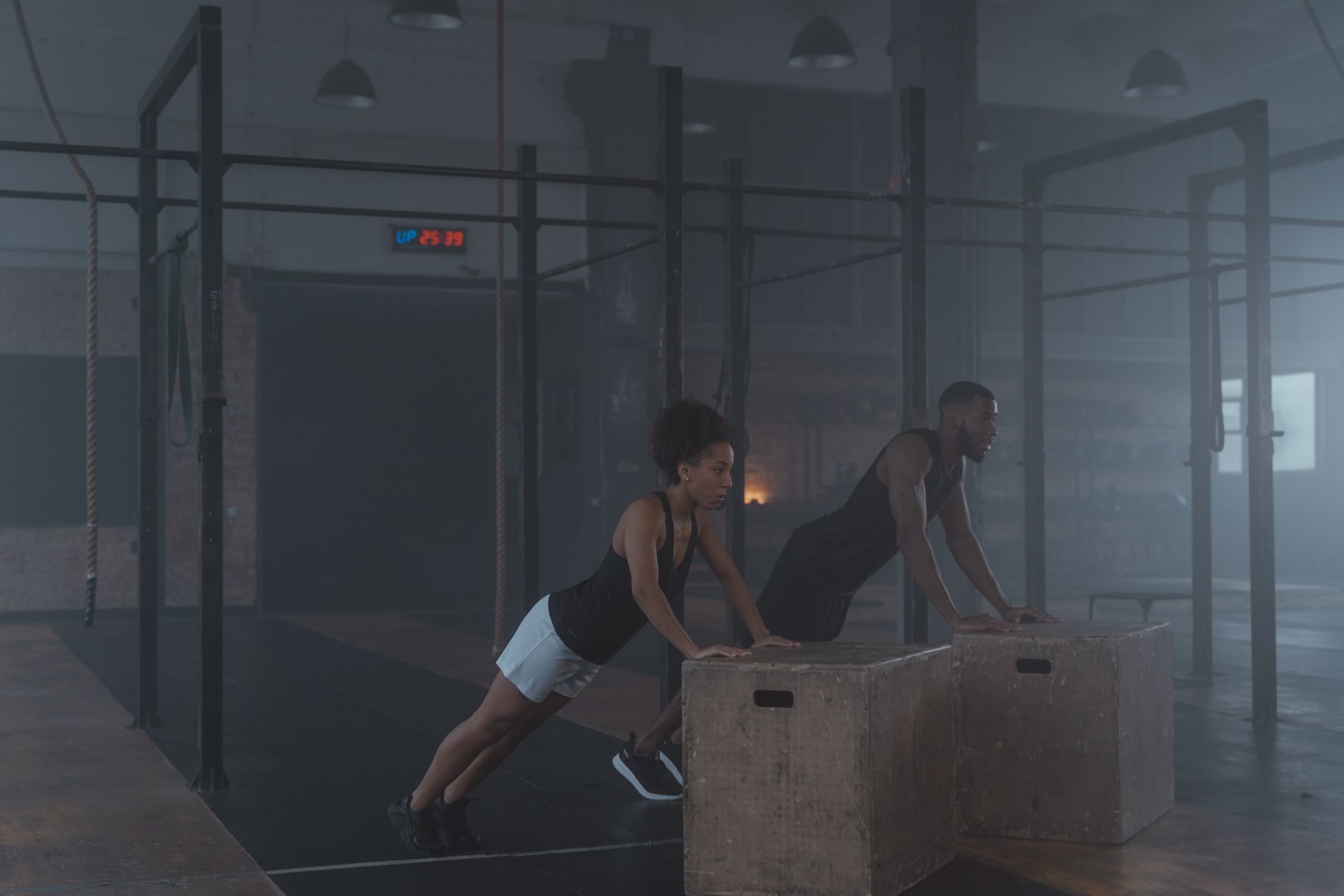 Two individuals engaging in strength training exercises indoors, showcasing fitness and endurance.