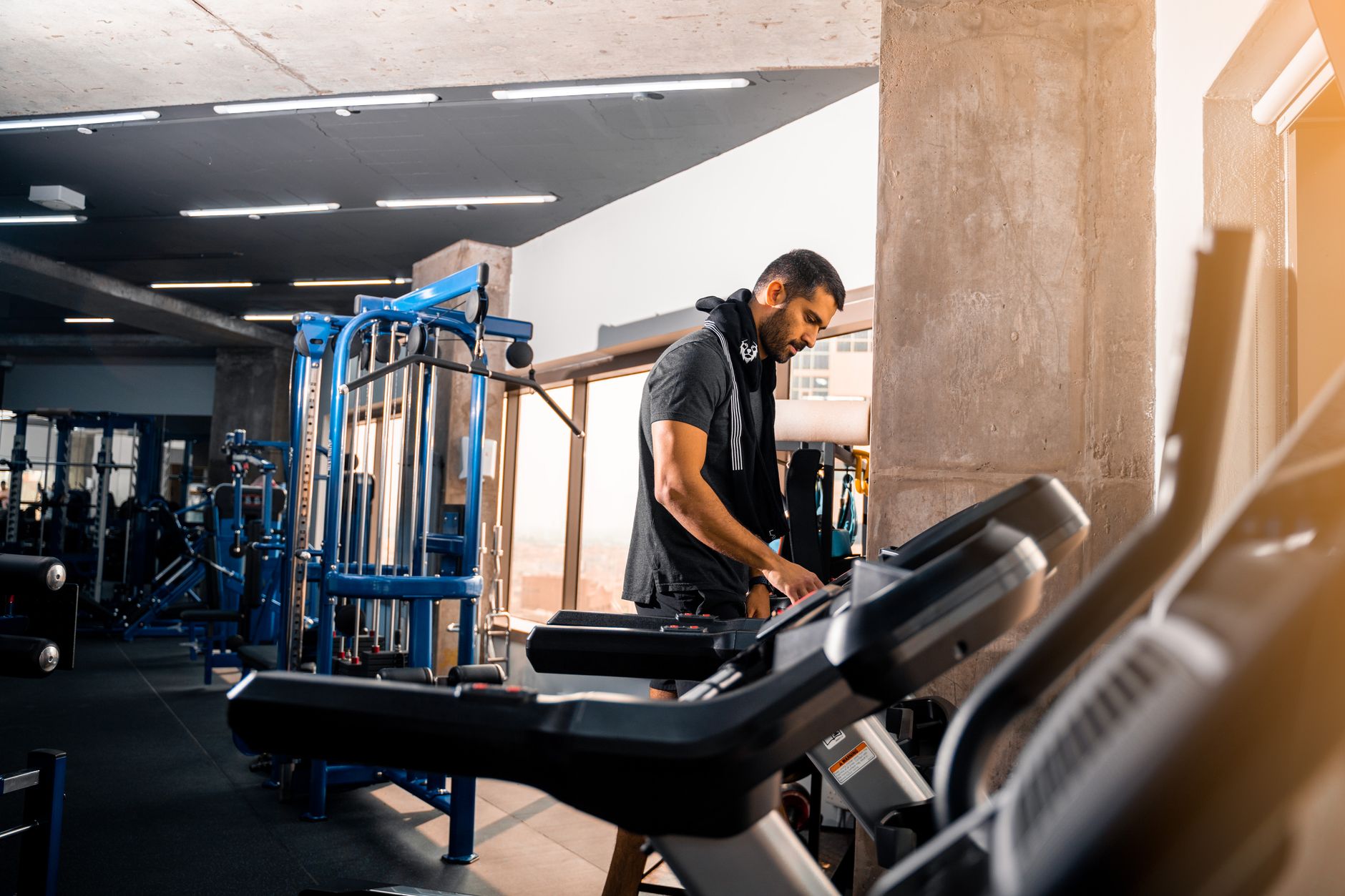 A man with short hair works out on a treadmill in a modern gym in Bahrain.