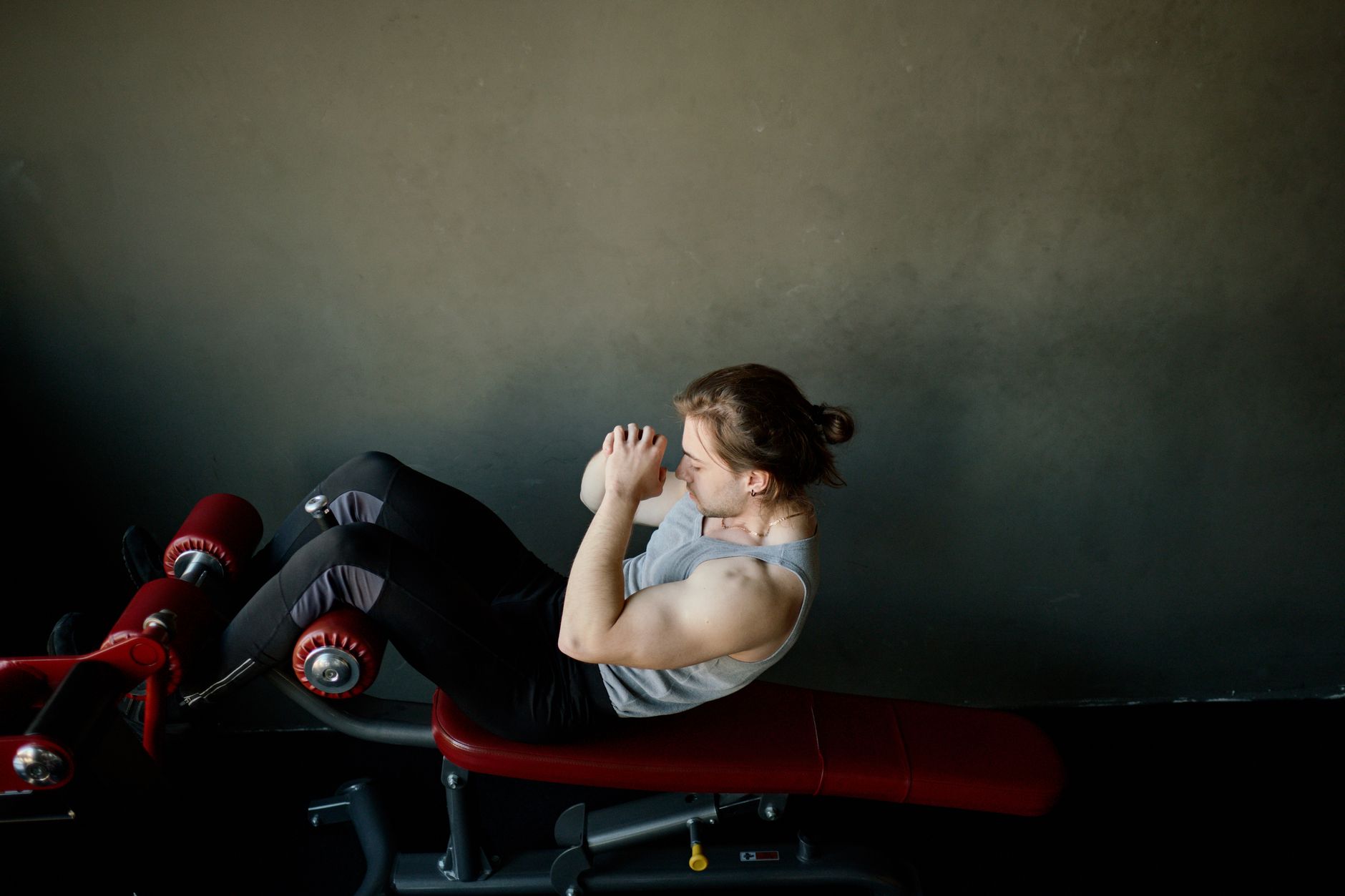 Focused young man doing abdominal exercises on a gym bench.
