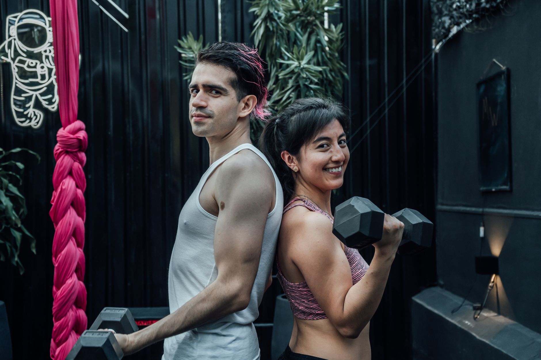 A fit man and woman posing back to back with dumbbells, promoting a healthy lifestyle.