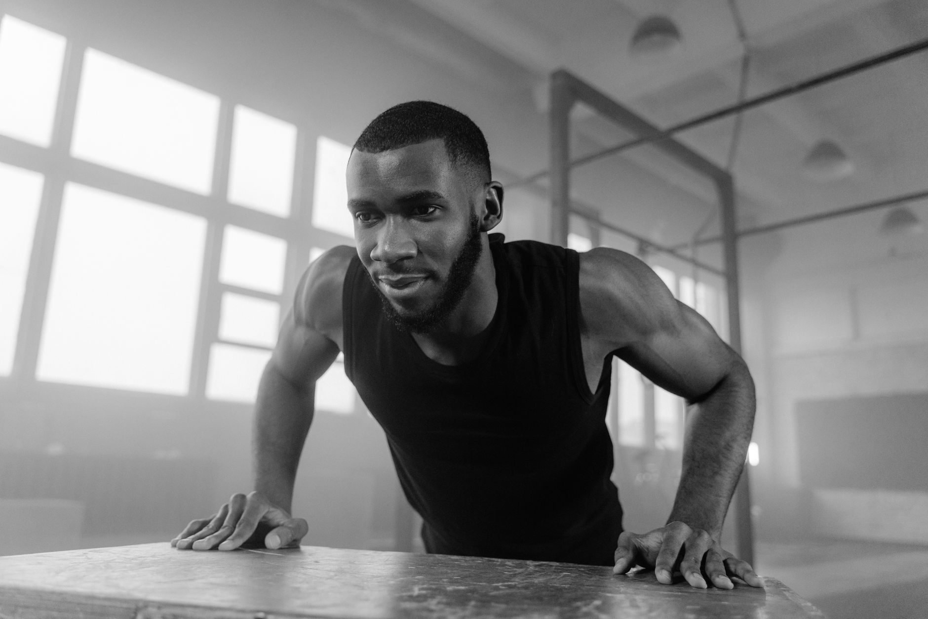 A focused man engages in a push-up exercise in a monochrome gym setting, epitomizing strength and fitness.