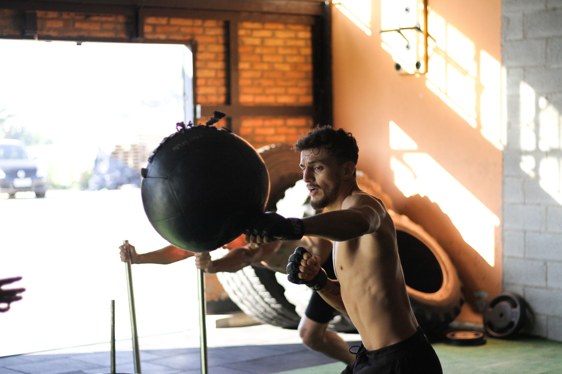 Athletic man practicing punching exercises with a bag indoors, demonstrating strength and focus.