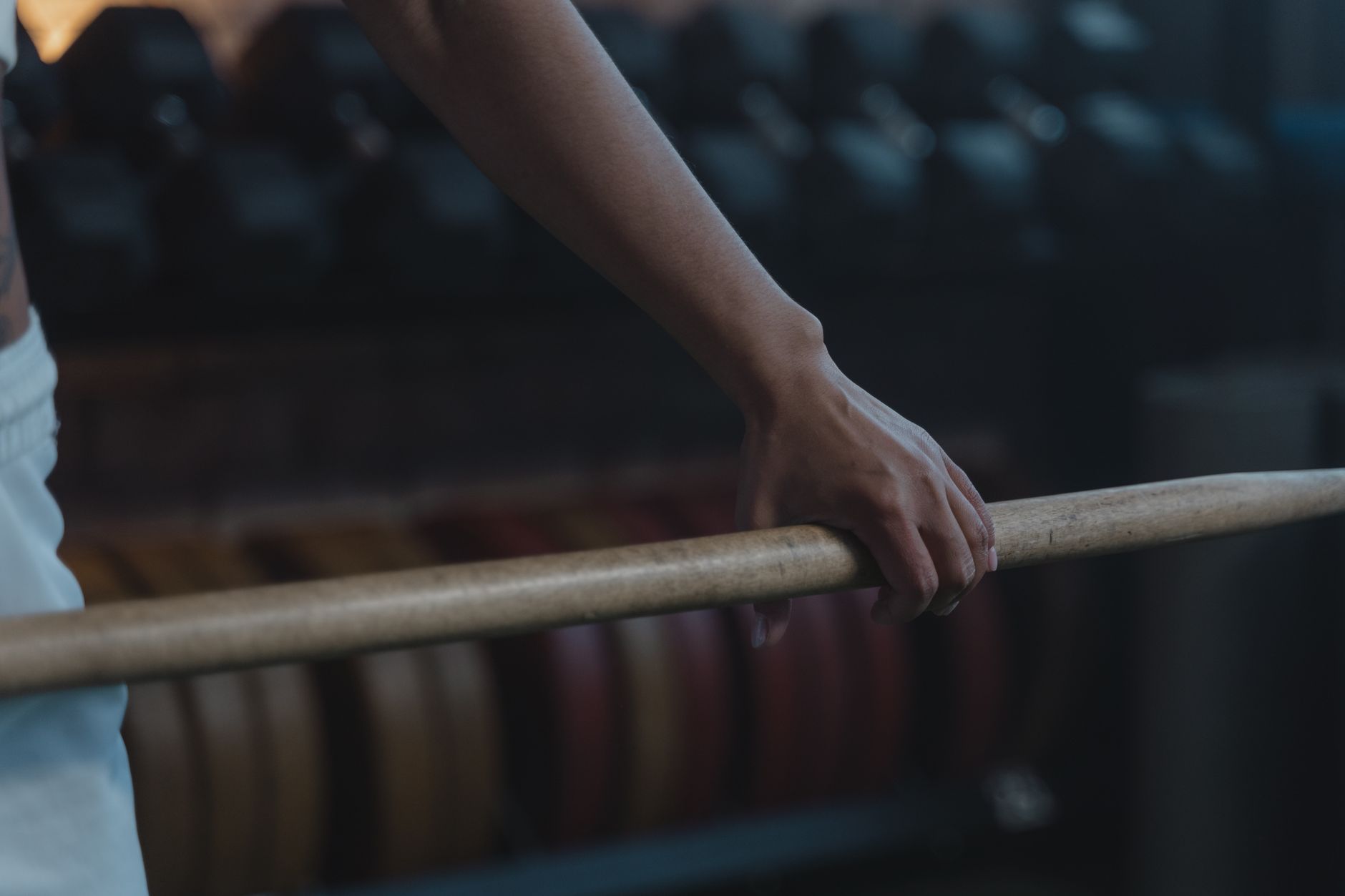Detailed view of an athlete's hand gripping a barbell, showcasing strength and focus in a gym setting.