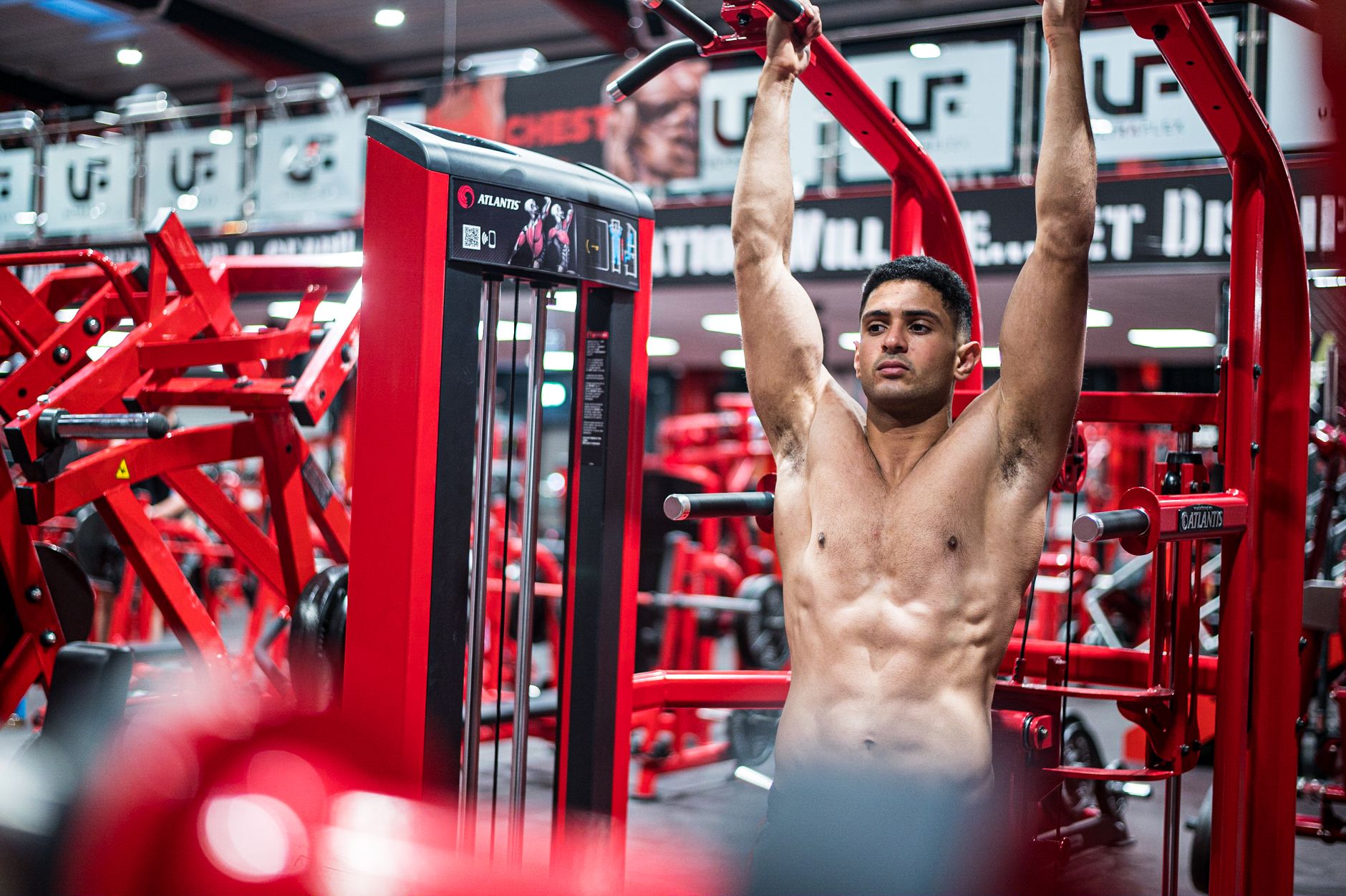 A muscular man exercising on gym equipment demonstrating strength and fitness indoors.