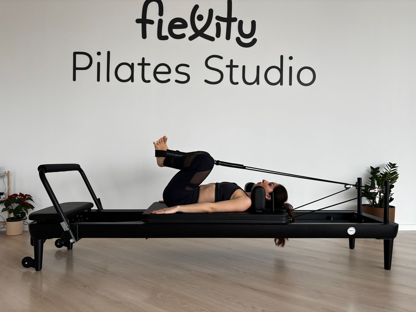 Woman practicing Pilates on a reformer machine in a modern studio setting.