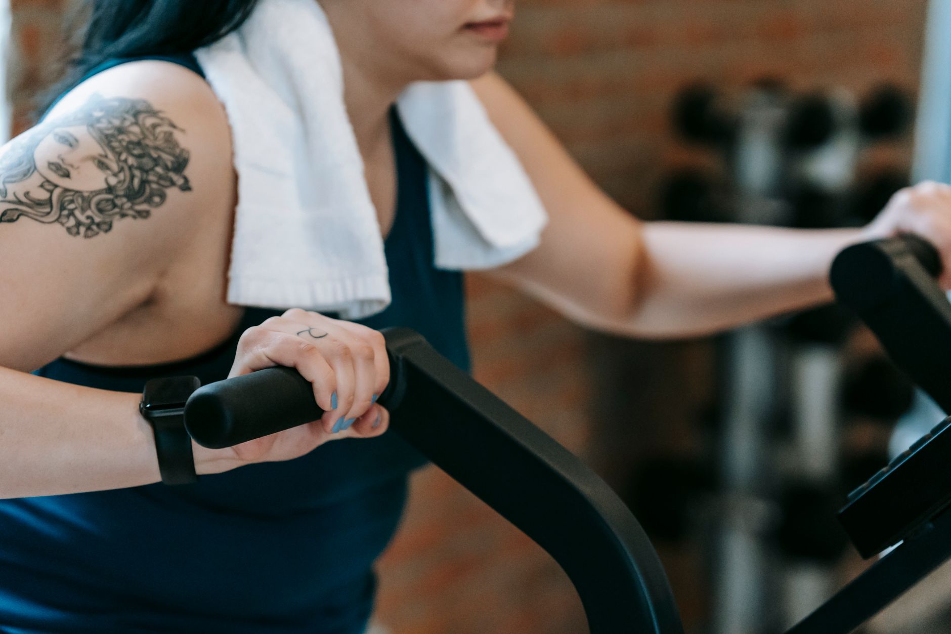 Side view of crop anonymous female in activewear training on exercise equipment and losing weight