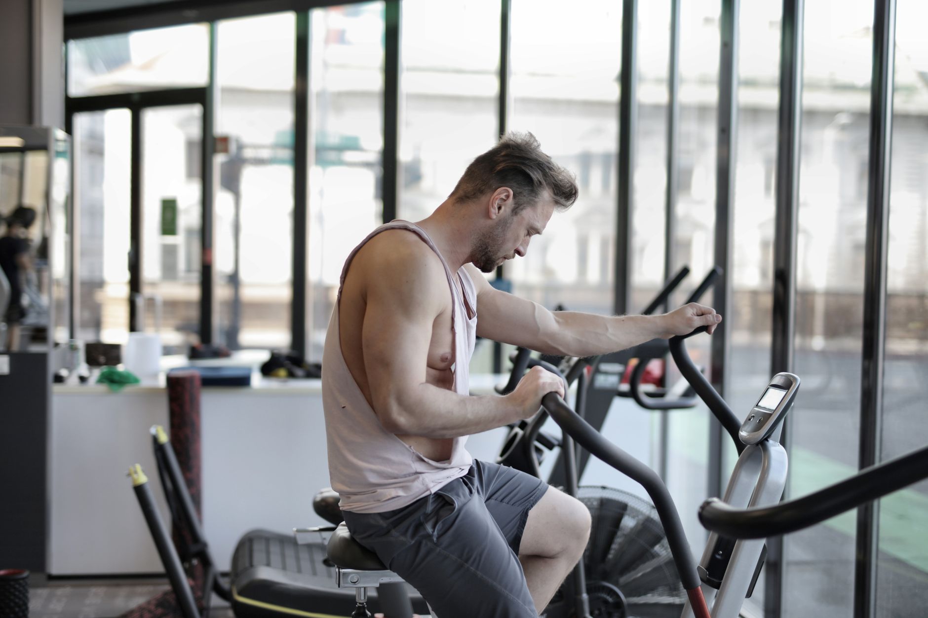 Side view of tired sportsman in activewear using exercise machine in modern gym and working on stamina