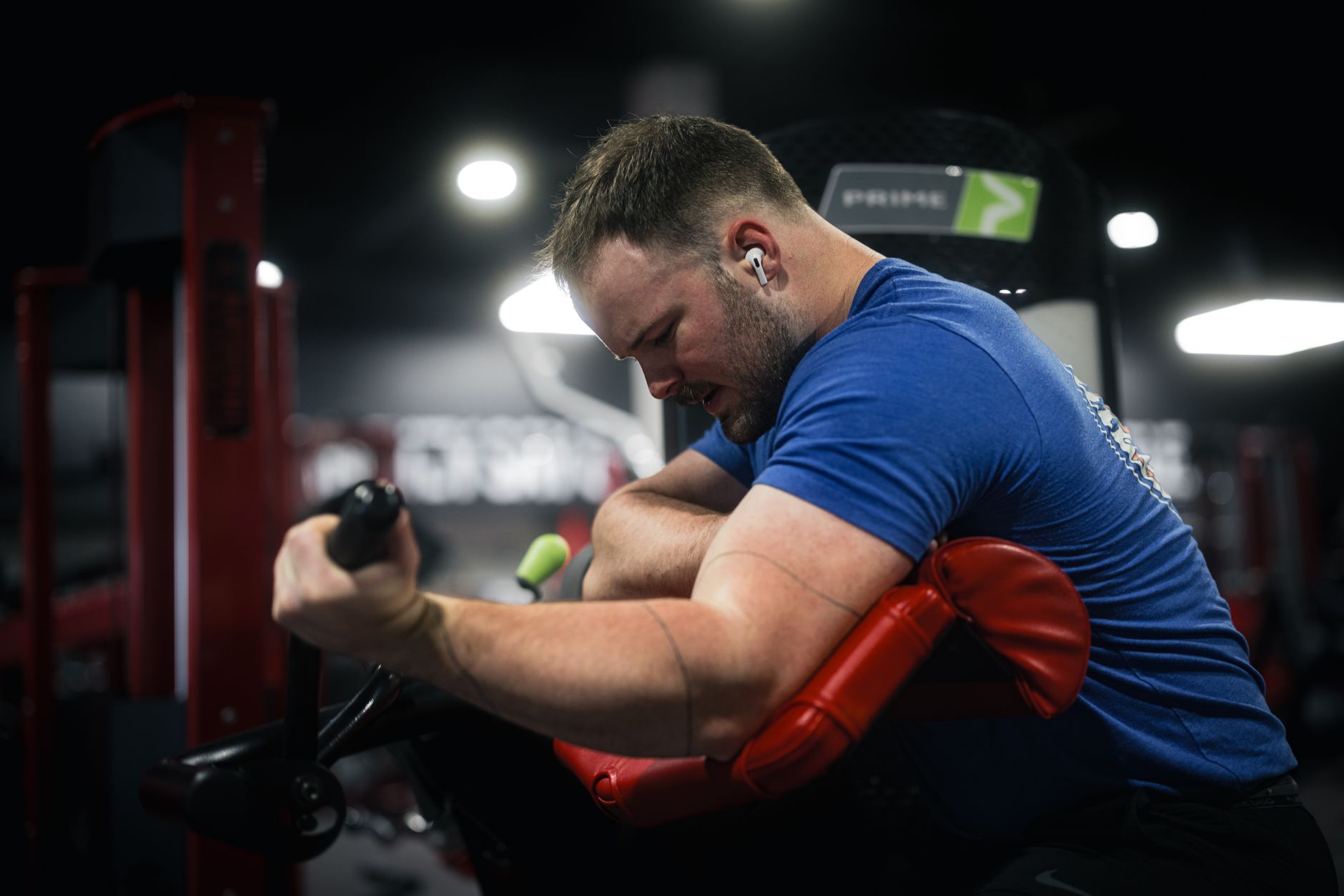 A determined man exercising on a gym bicep machine, showcasing dedication and focus.