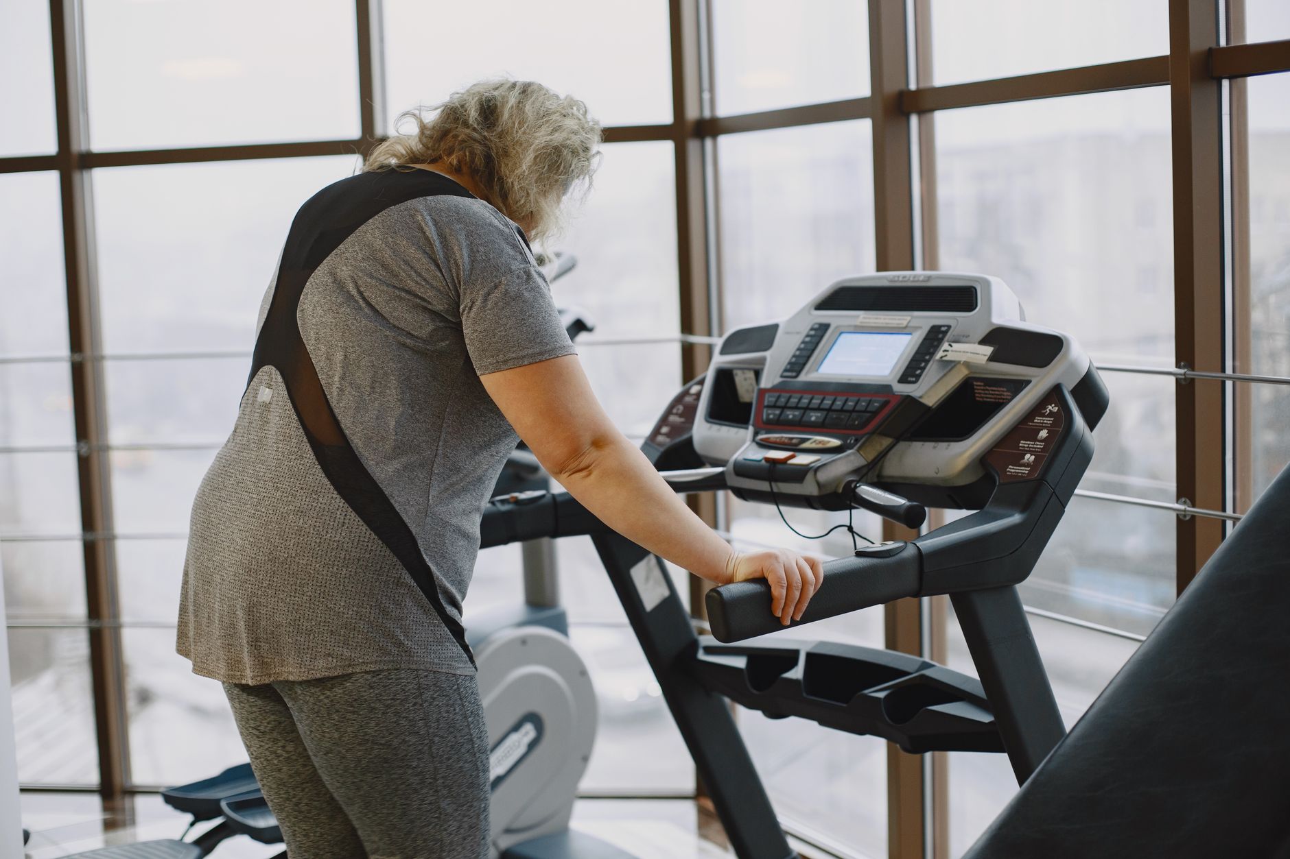 A senior woman using a treadmill at the gym, focusing on fitness and wellbeing.
