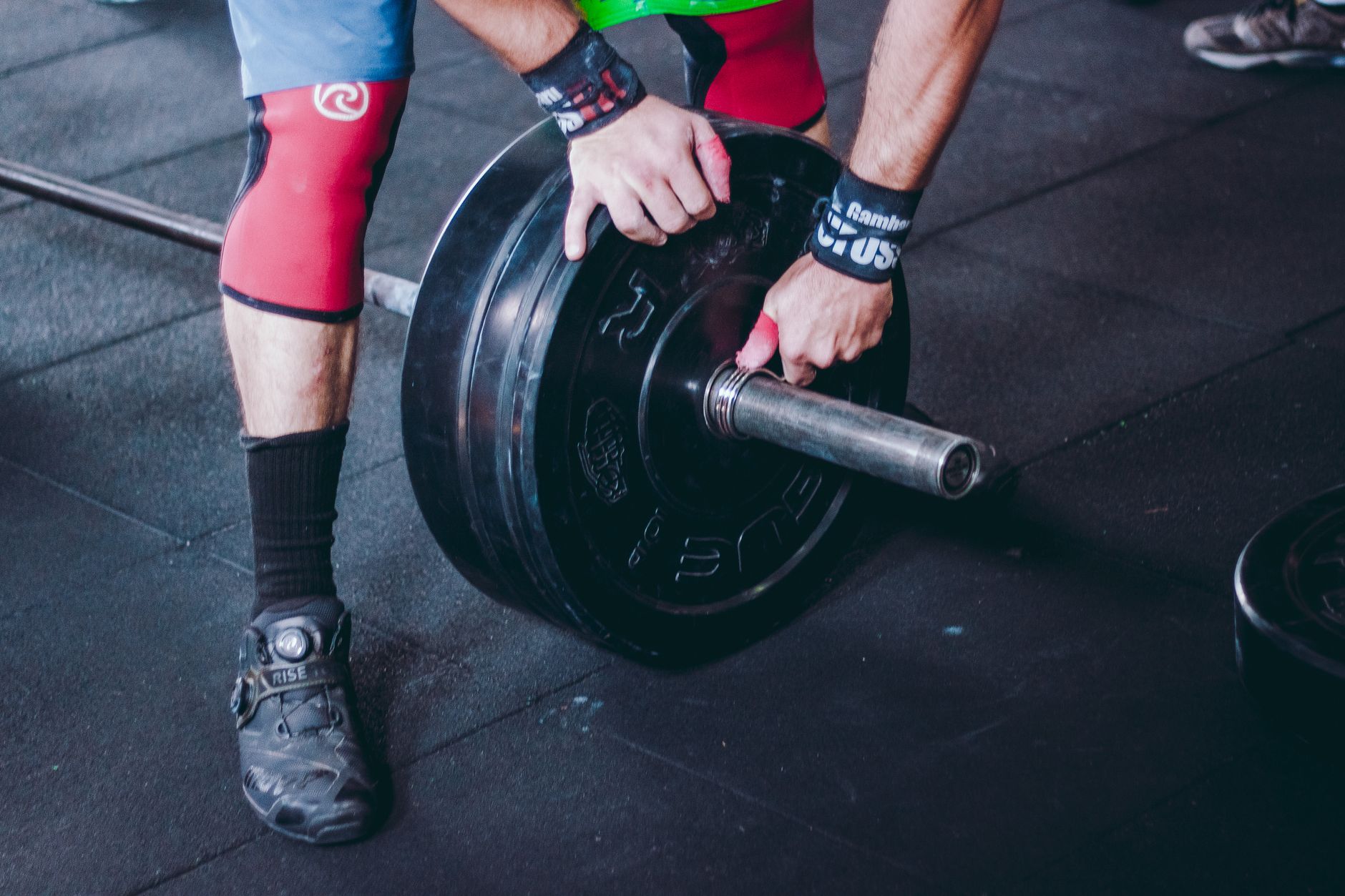 Athlete adjusting weights on a barbell in a gym setting, highlighting fitness and strength.
