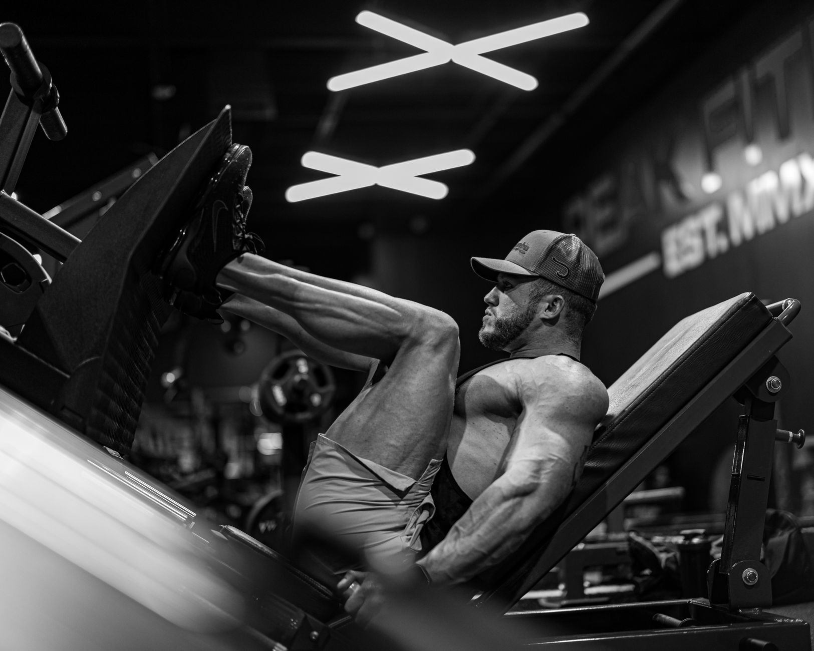 Strong muscular man performing leg press exercise in a modern gym setting.