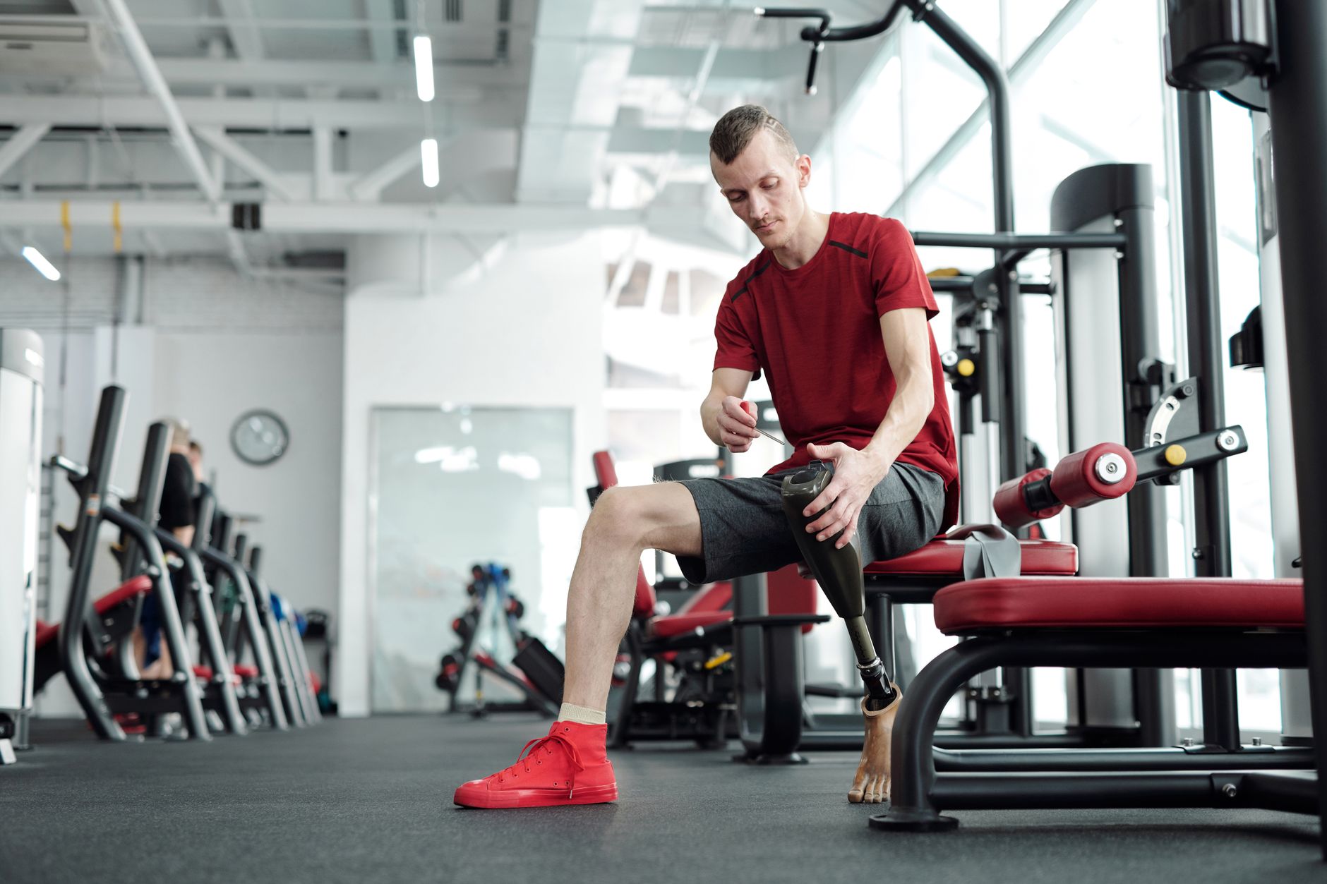 A man with a prosthetic leg working out in a modern gym. Showcases strength and determination.