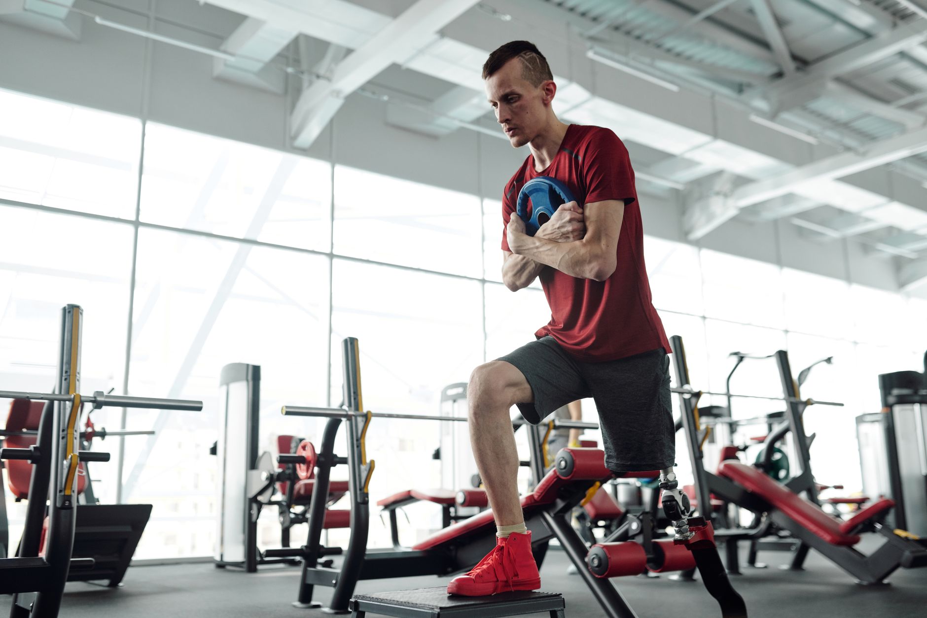 Determined male athlete with prosthetic leg training in a modern gym. Fitness and strength focus.
