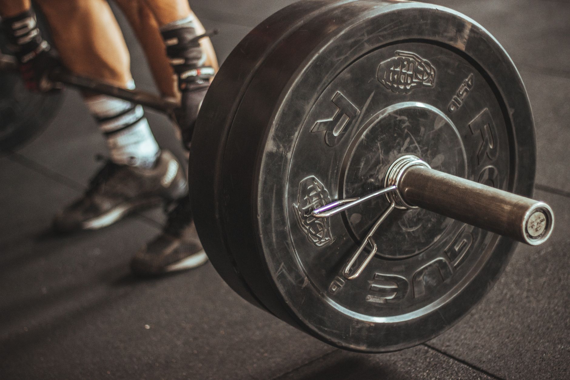 Close-up of a weightlifter's legs and barbell during a workout session.