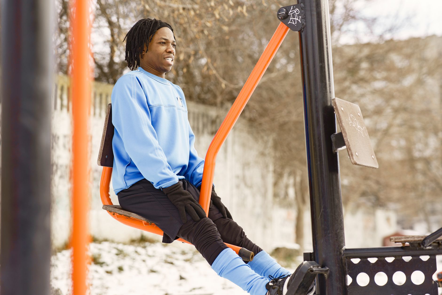 Man exercising on outdoor gym equipment in winter.