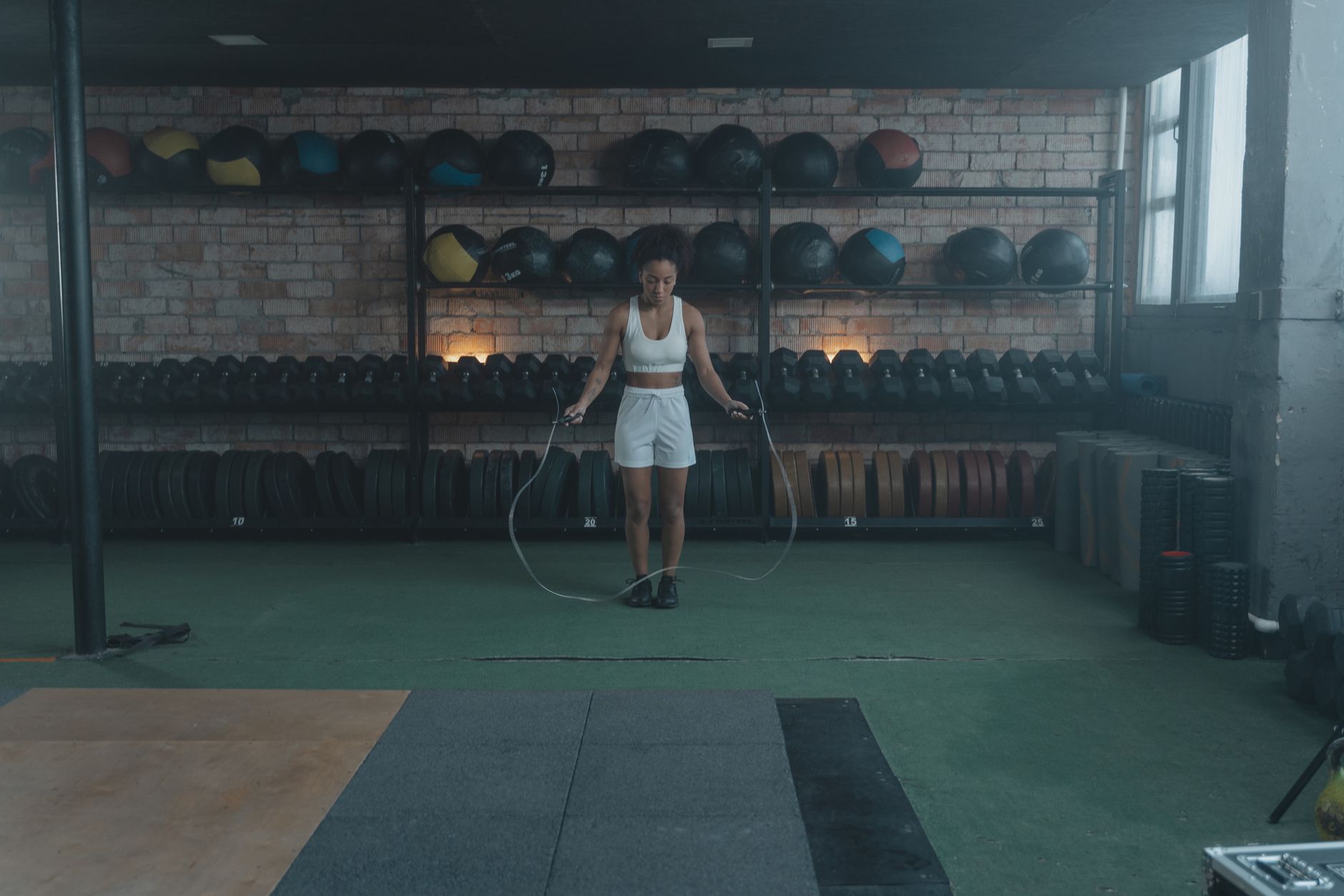 An athletic woman in a gym jump roping, symbolizing fitness and a healthy lifestyle.