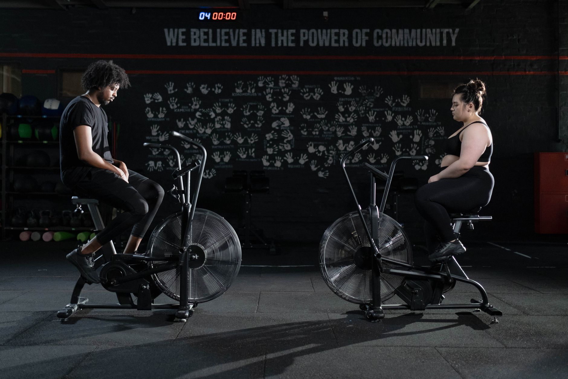 Two people on stationary bikes in a gym, reflecting community strength.