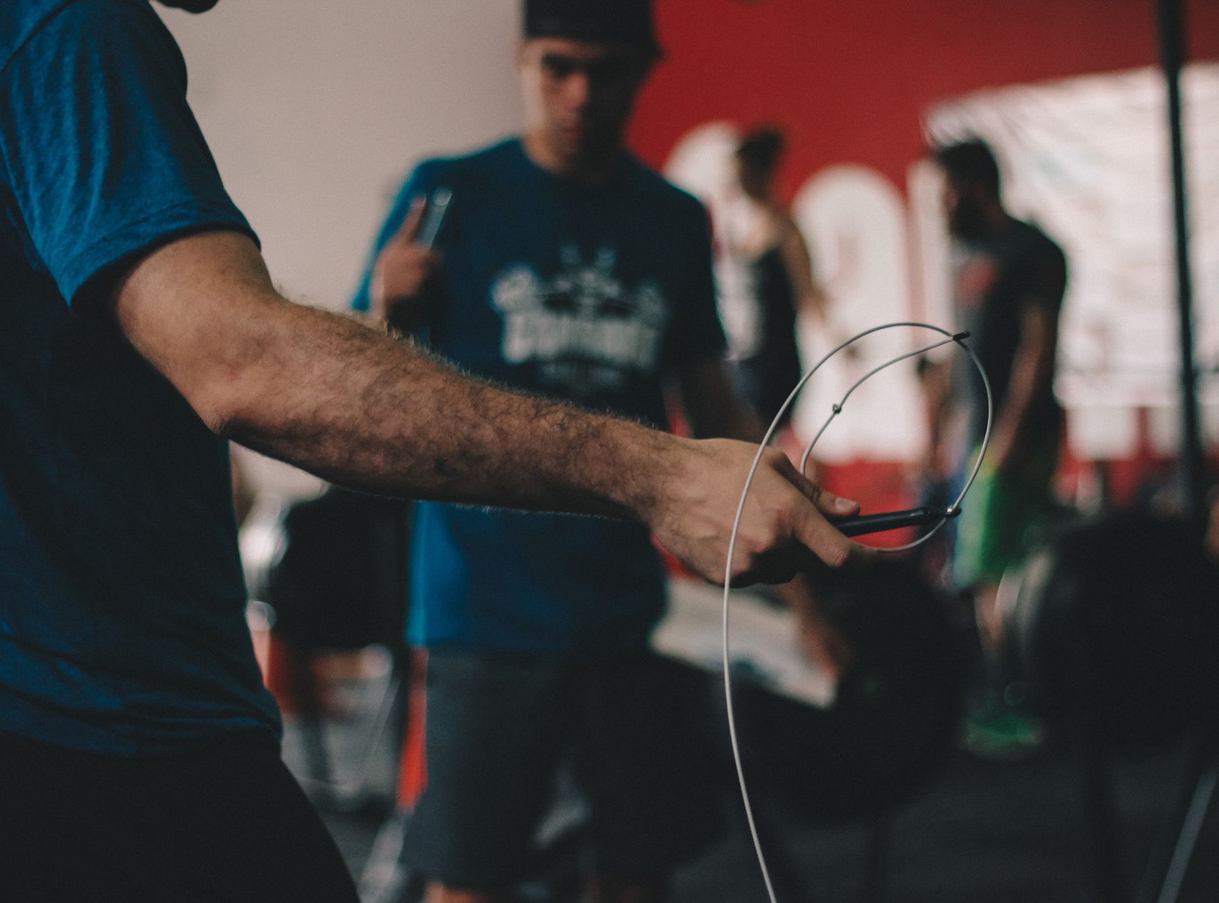 Adult man performing jump rope exercise indoors at a gym during the day.