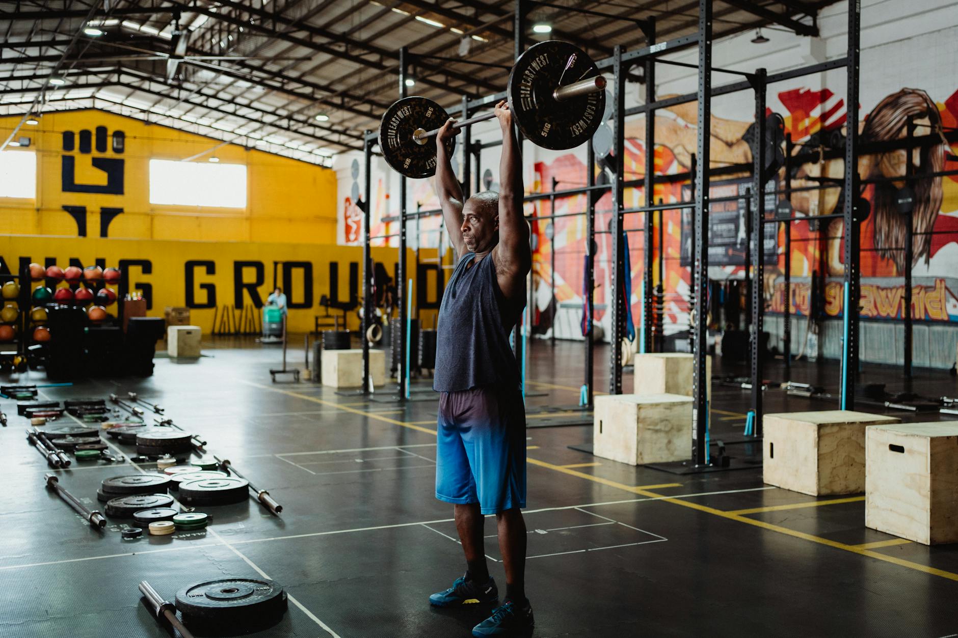 Adult man performing weightlifting exercise in an industrial-style gym, showcasing strength and fitness.