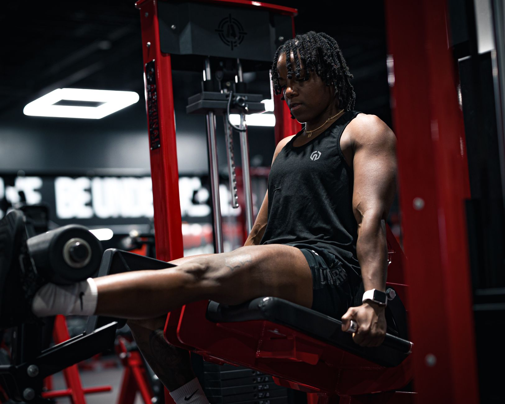 Muscular individual focusing on leg exercises in a gym setting, emphasizing strength and fitness.