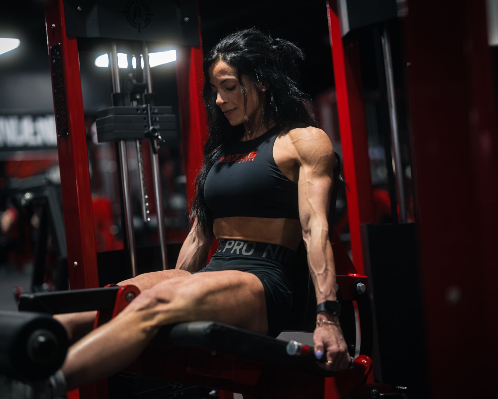 Strong female bodybuilder working out with weights in a gym environment.