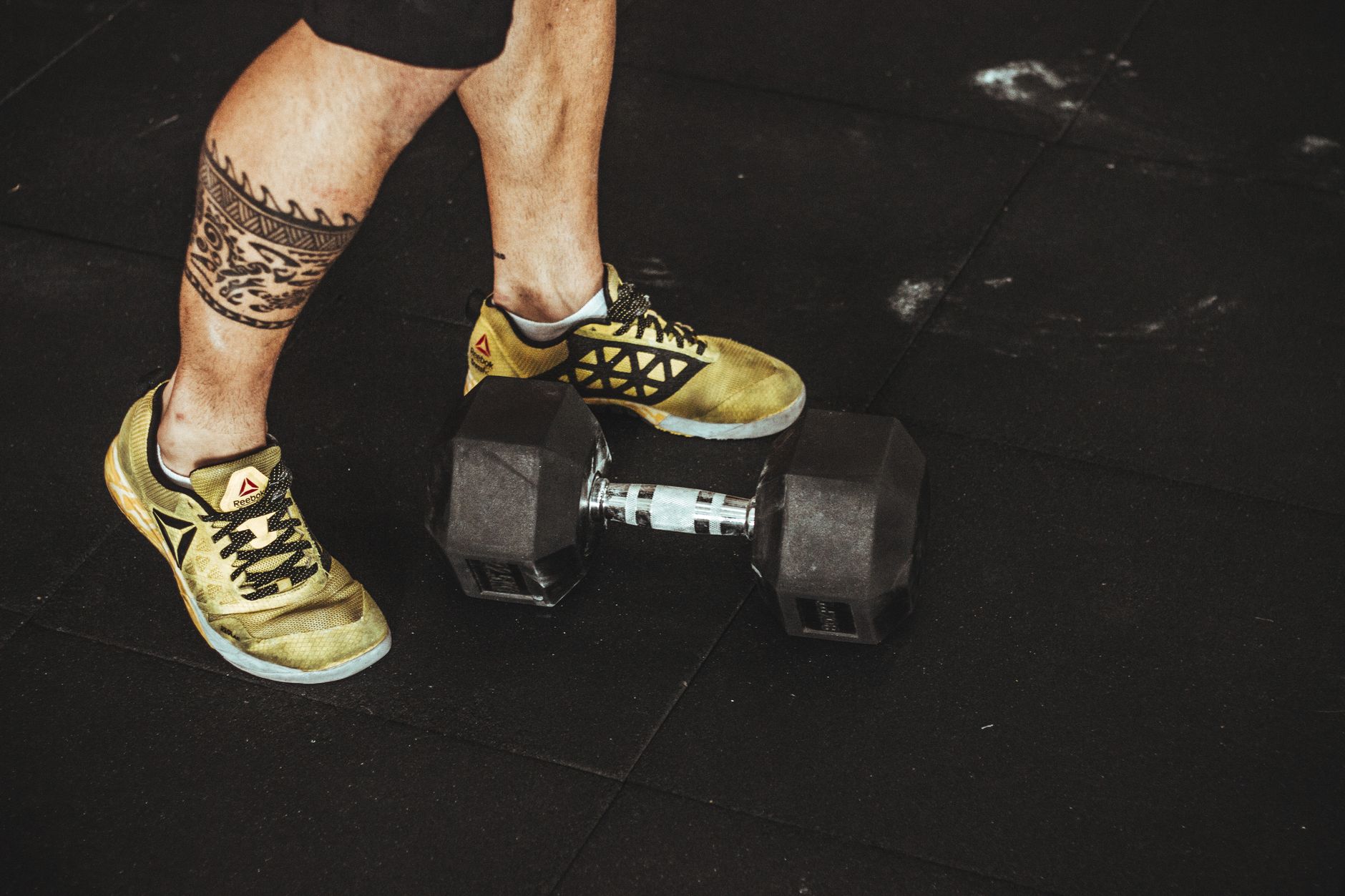 Close-up of yellow athletic shoes and a dumbbell in a gym setting, emphasizing fitness and style.