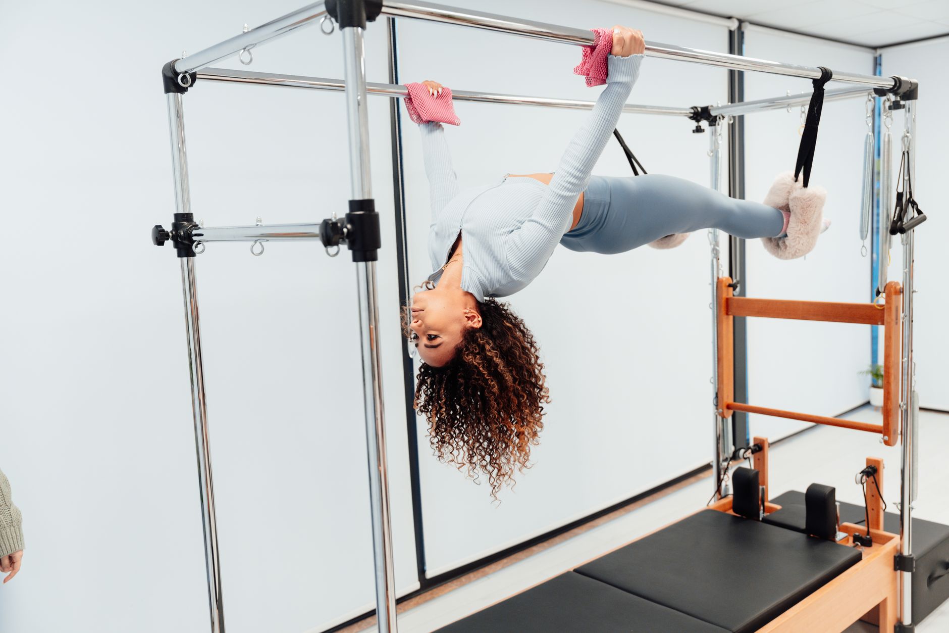 Fit woman doing pilates exercise on reformer equipment in a fitness studio.