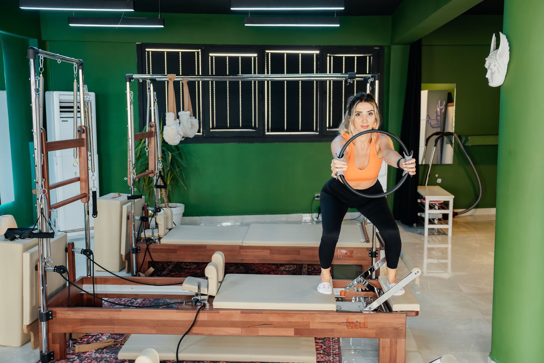Fitness enthusiast practicing Pilates on a reformer machine in a modern, brightly lit studio.