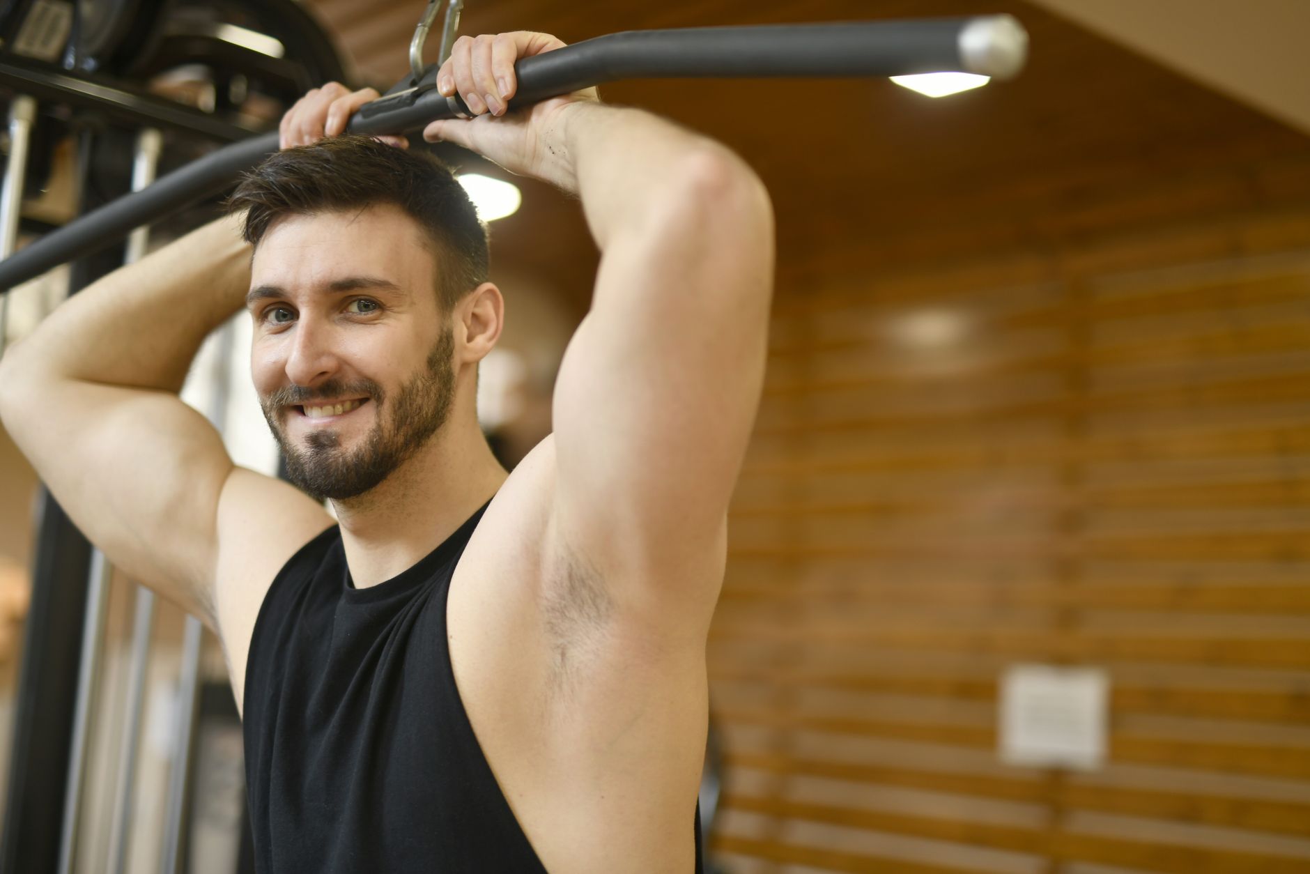 Confident man working out on gym equipment, showcasing strength and fitness indoors.