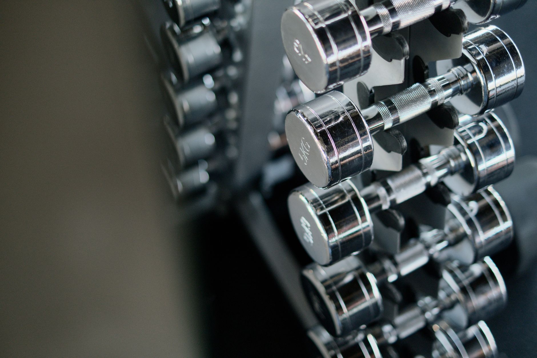 Close-up of chrome dumbbells neatly arranged on a rack in a modern fitness gym.