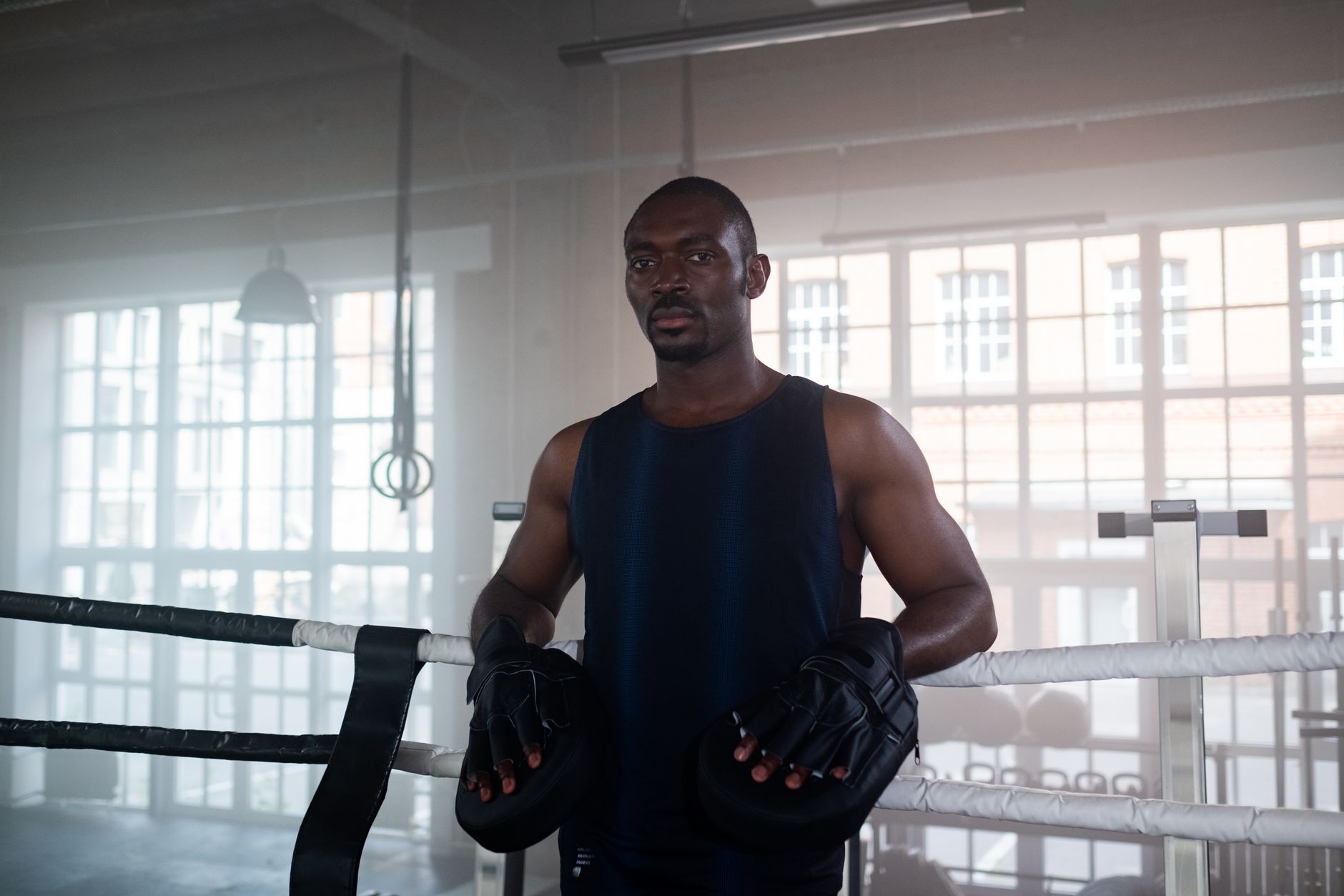 Determined boxer standing in a boxing ring, ready for training indoors.
