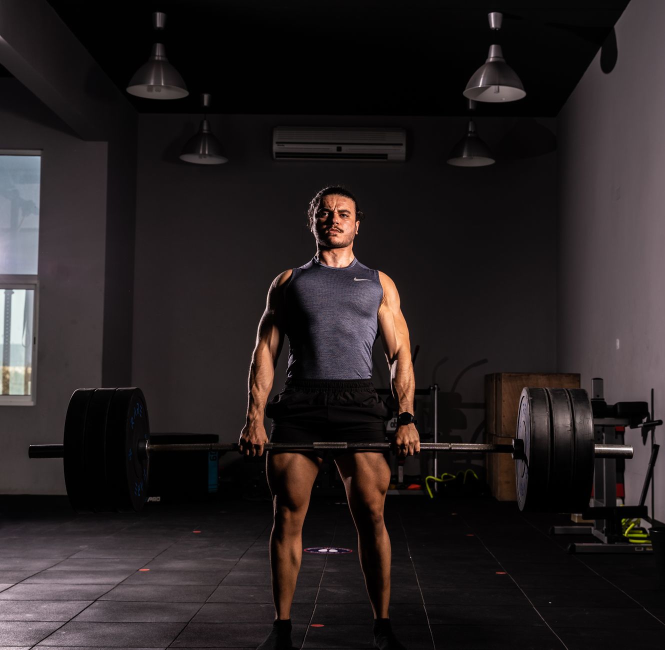 A strong adult man lifting a large barbell indoors, showcasing strength and fitness.