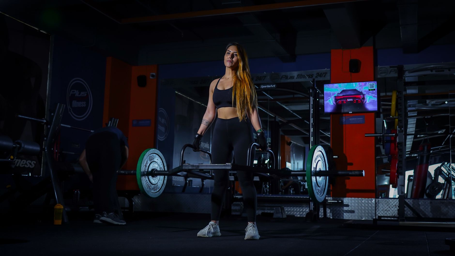 A woman powerlifting inside a gym, embodying strength and fitness during a workout session.