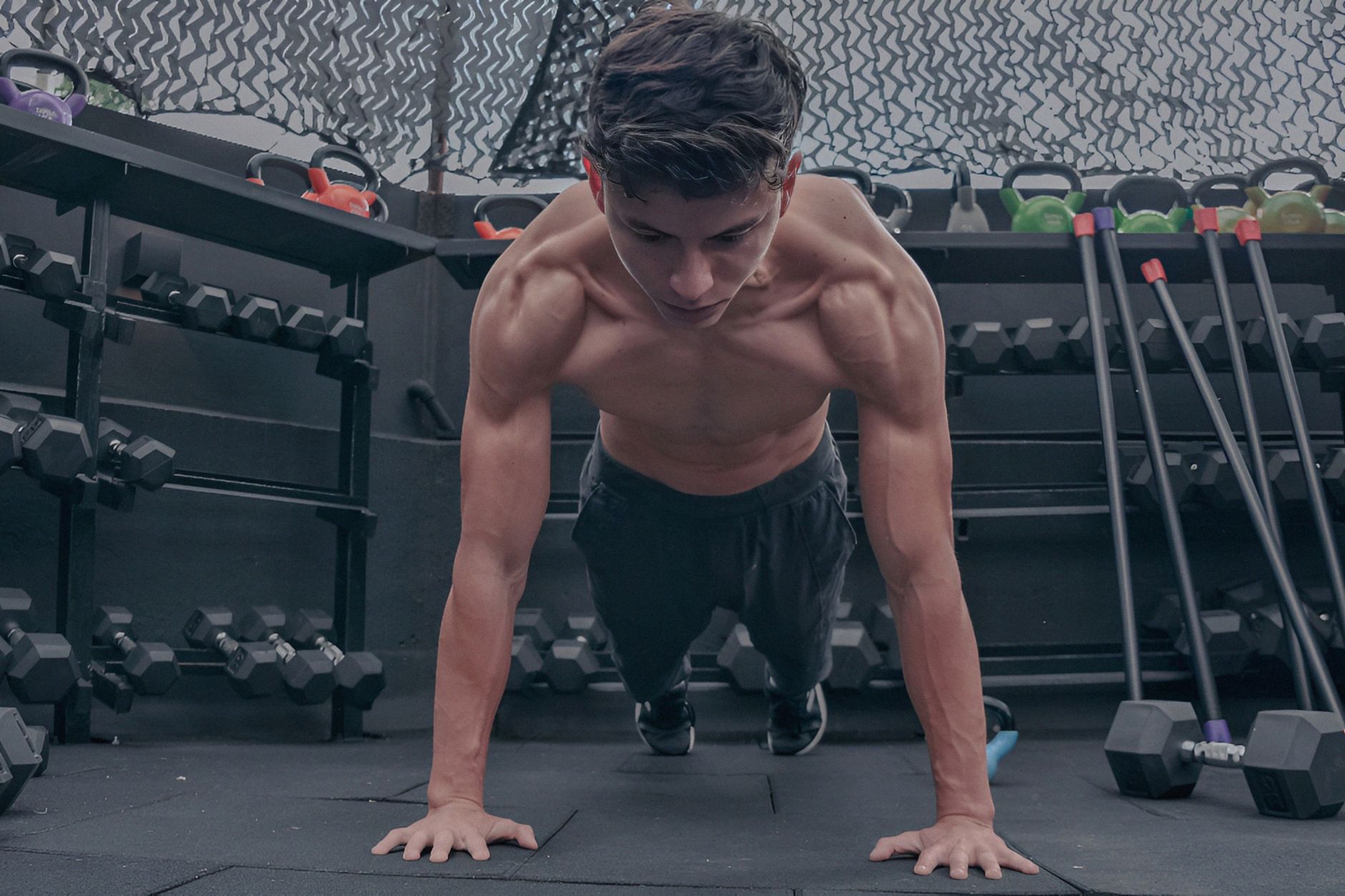 A muscular young man doing push ups in a modern gym setting