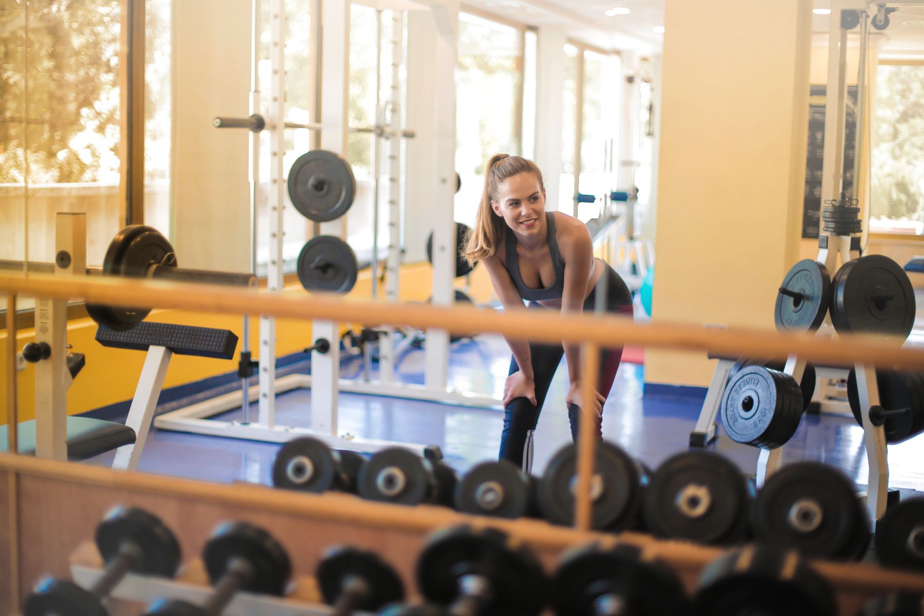 Fit woman in a gym with weights, showcasing strength and fitness lifestyle.