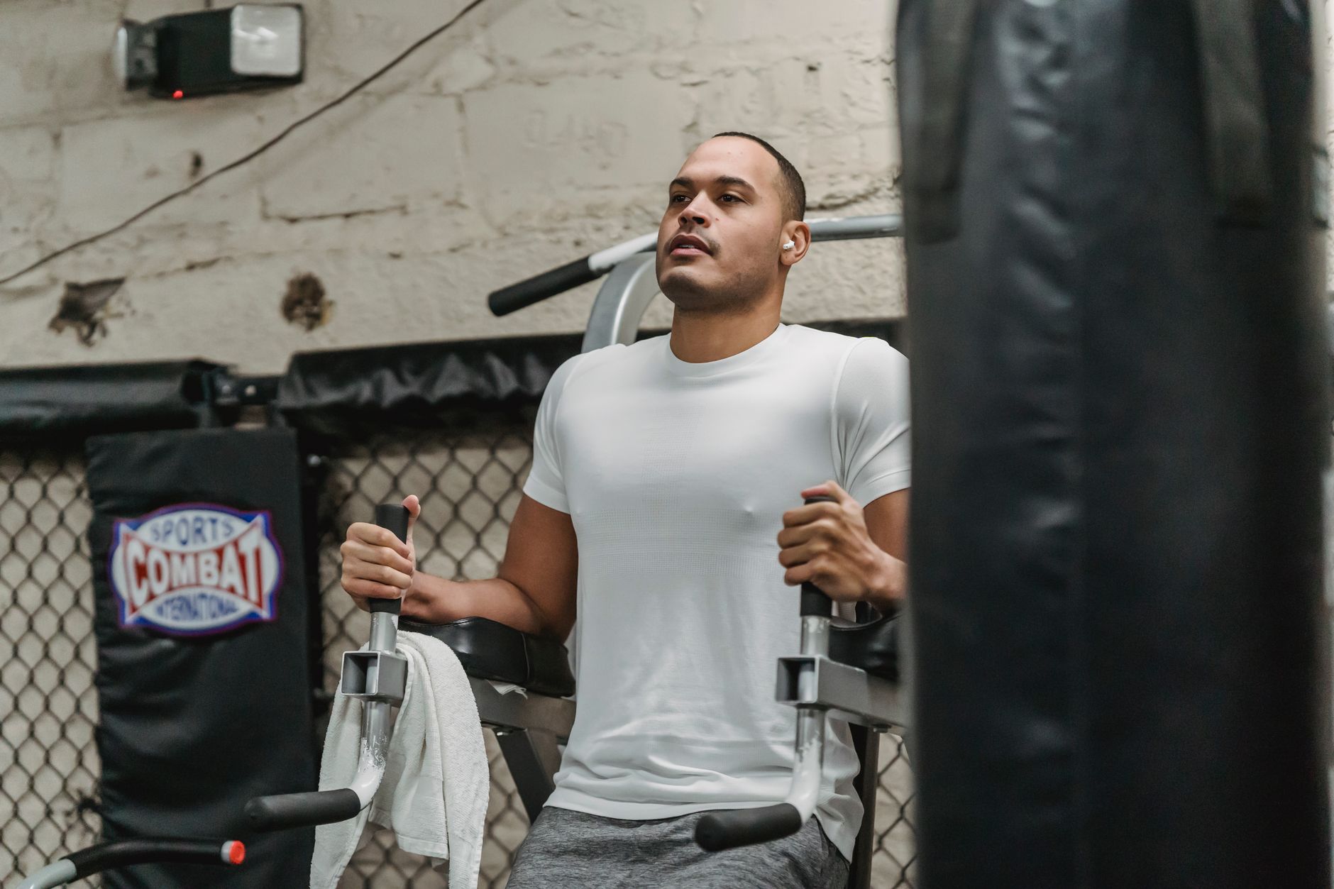 Focused sportsman doing knee to chest exercise for abdomen muscles on machine during intense workout in modern gym