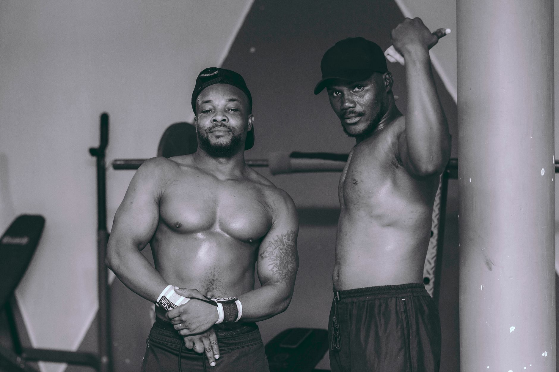 Two fit men posing confidently in a gym setting, showcasing fitness and strength.