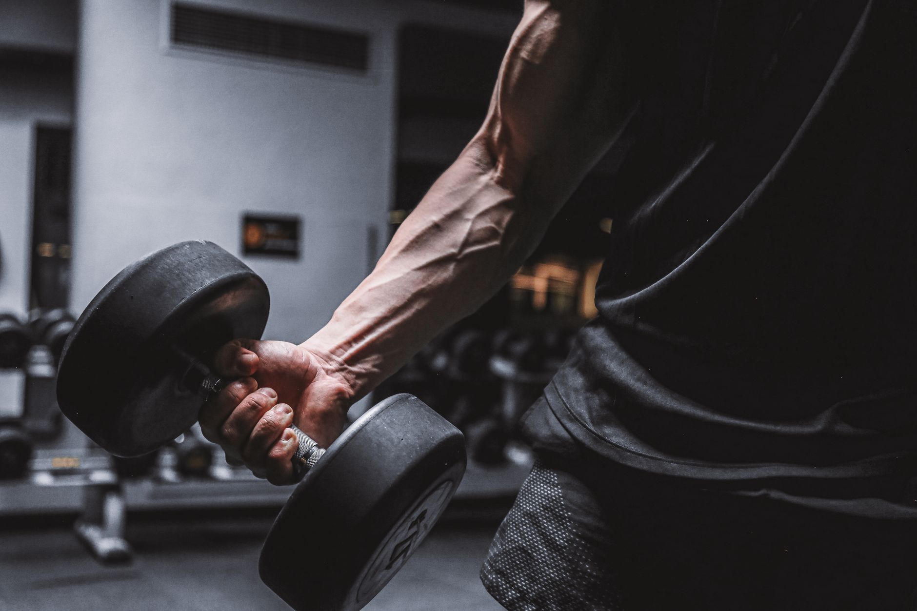 Close-up of a muscular arm holding a dumbbell, emphasizing strength and fitness.