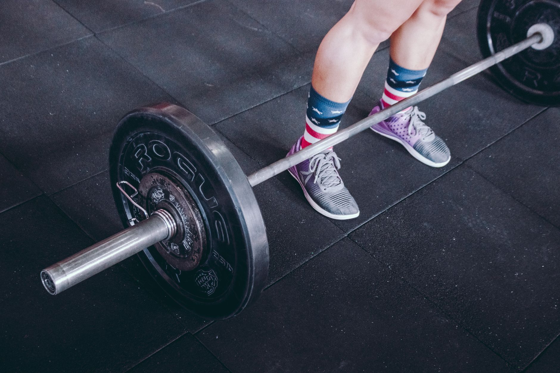 Person preparing to lift a barbell with patriotic socks in a gym.