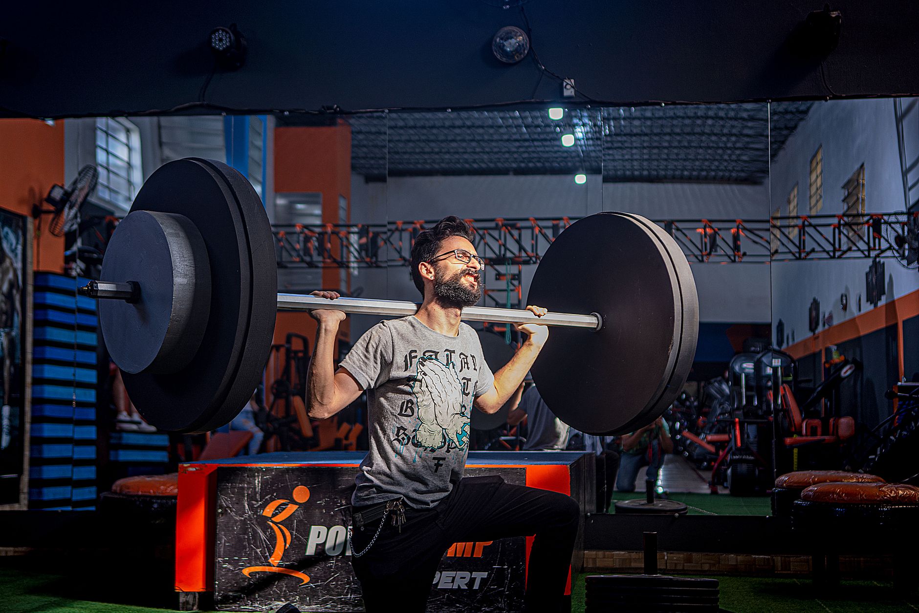 Adult male lifting a barbell in a gym, showcasing strength and fitness.